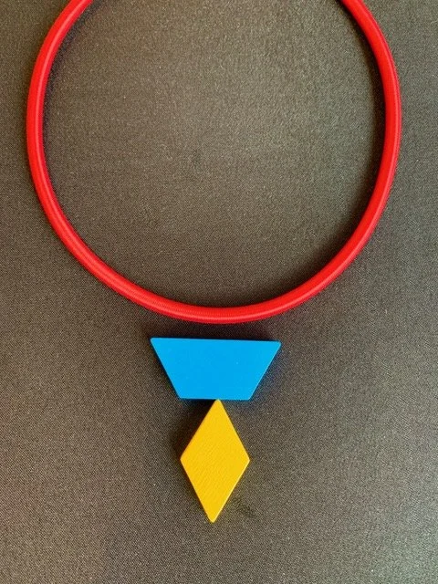 A red circular ring above a blue triangle, a yellow diamond, and a black background. Created by Theresa Killgore.
