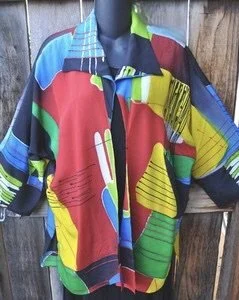 Colorful geometric patterned long-sleeve shirt hanging on a wooden background.