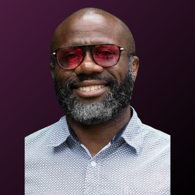 Headshot of smiling male professional with glasses wearing a blue shirt.