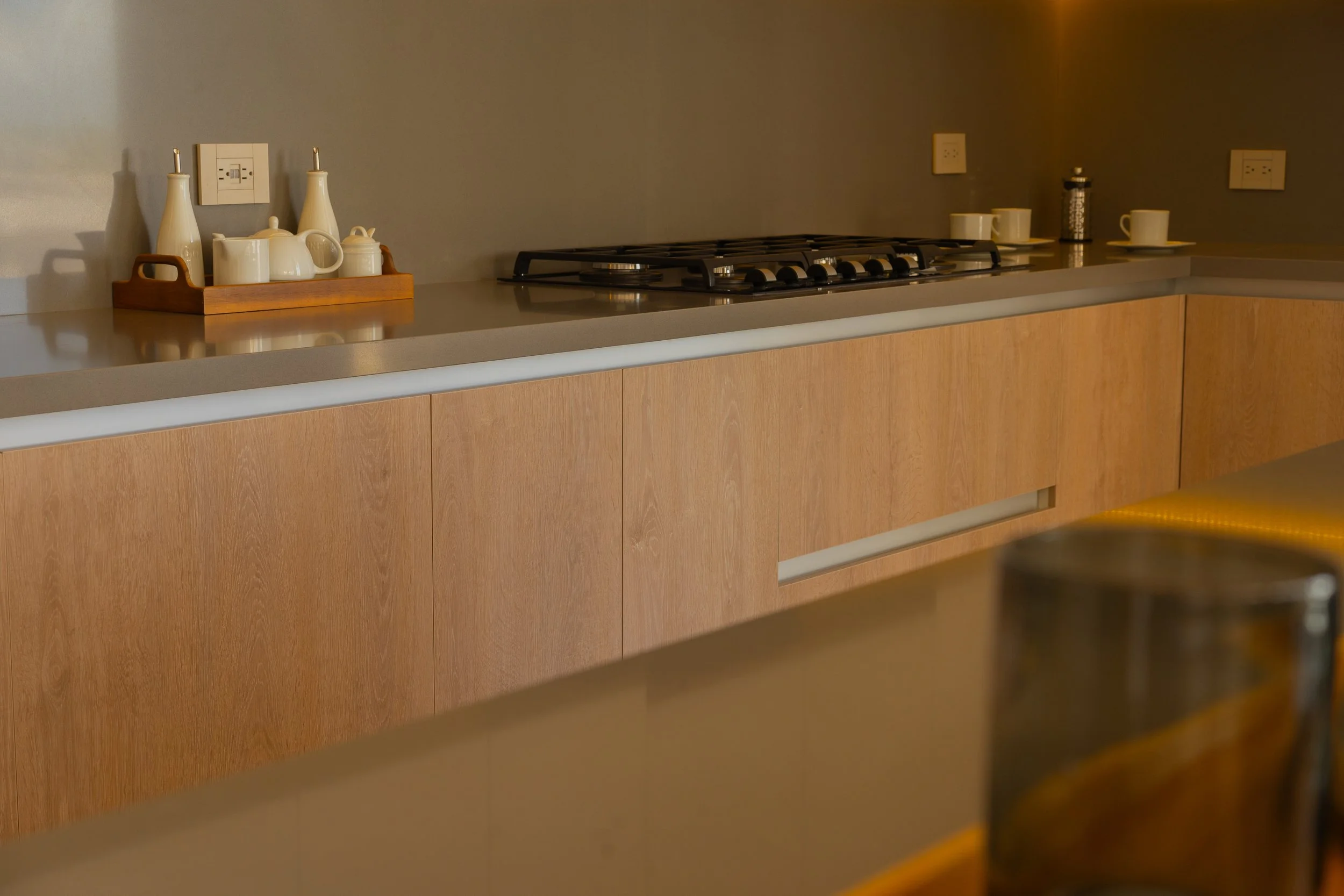 Kitchen countertop with teapot, bottles, cups, and a stove.