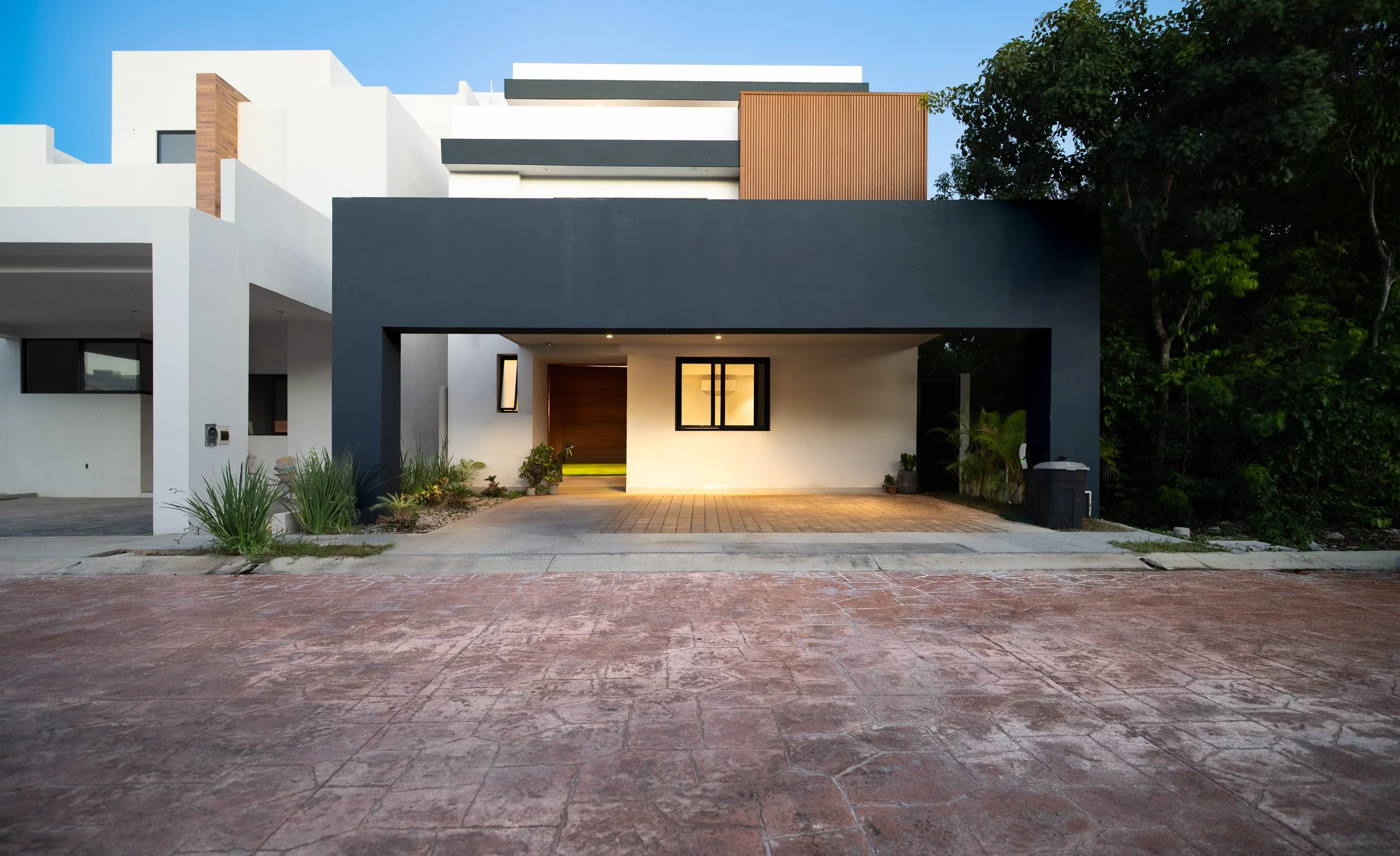 Modern two-story house with white and charcoal exterior, wood accents, covered driveway, and landscaped entrance