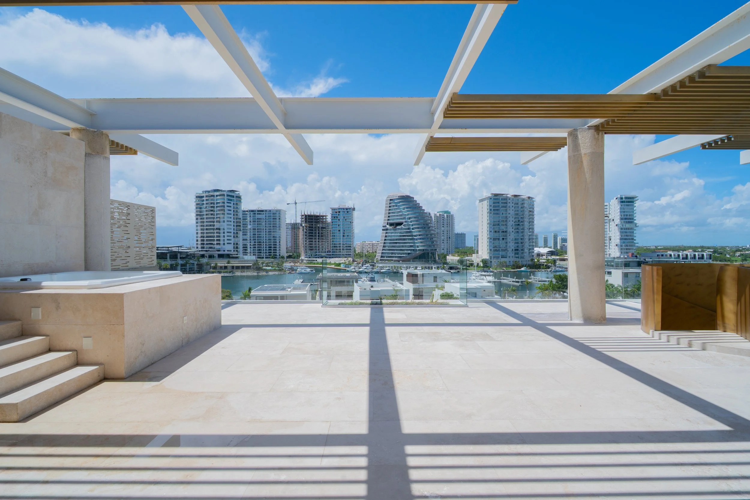 Luxury rooftop terrace overlooking a marina, modern high-rise buildings, and blue sky