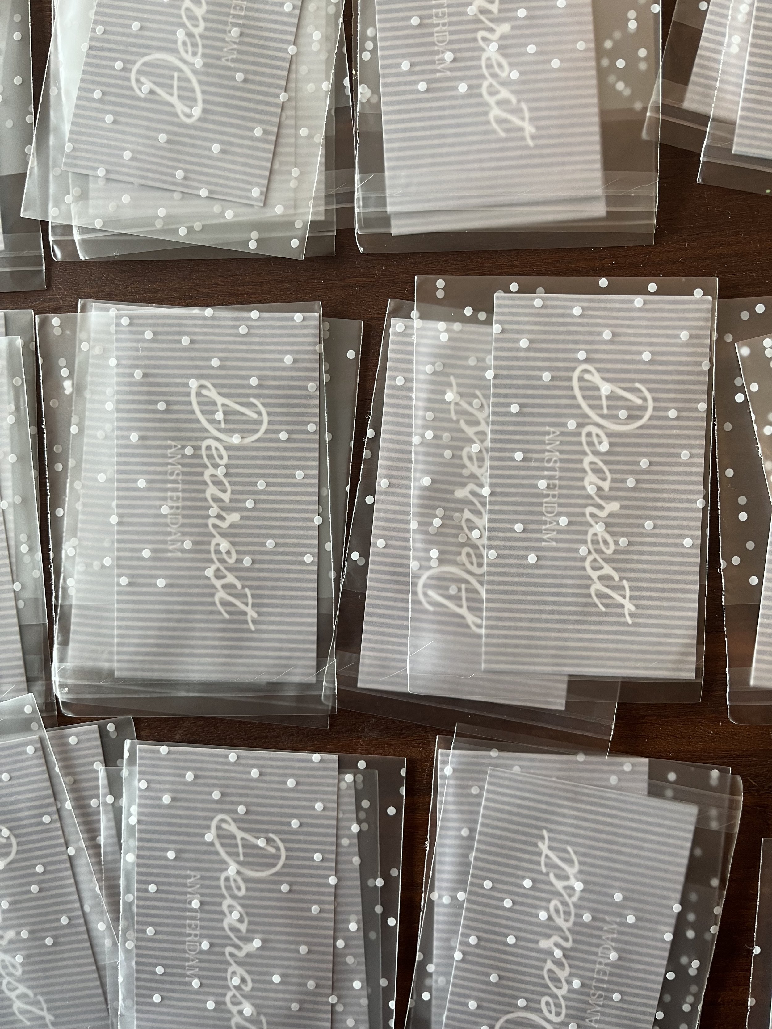 Multiple clear plastic envelopes with white polka dots and cursive writing that says 'Decorations,' placed on a wooden surface.