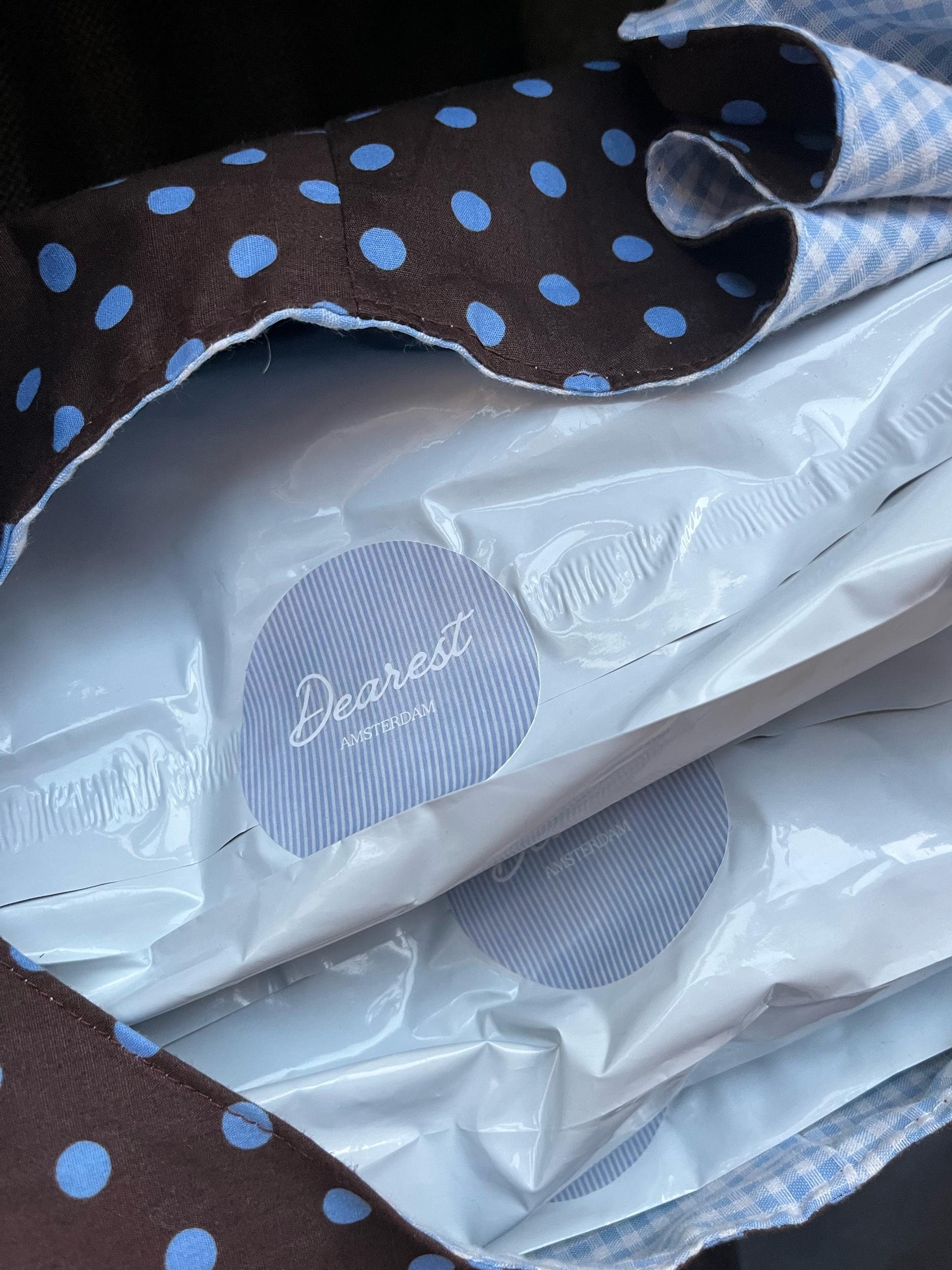 Close-up of a bag filled with Dearest Amsterdam packages. The bag has brown fabric with blue polka dots.