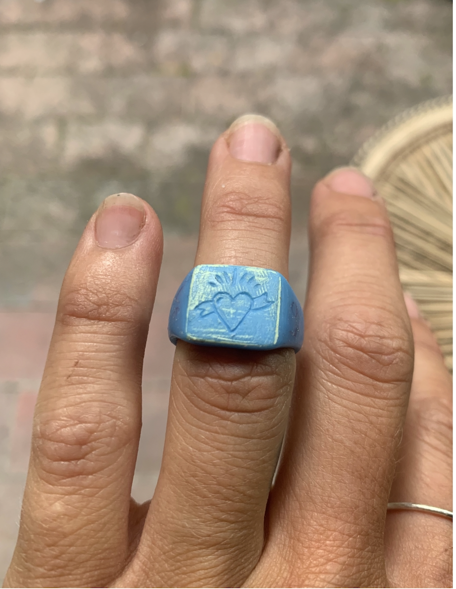 Hand wearing a signet ring carved from wax with a heart on it