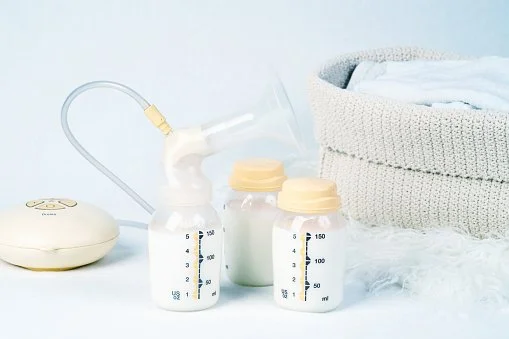 Bottles of expressed milk next to a breast pump