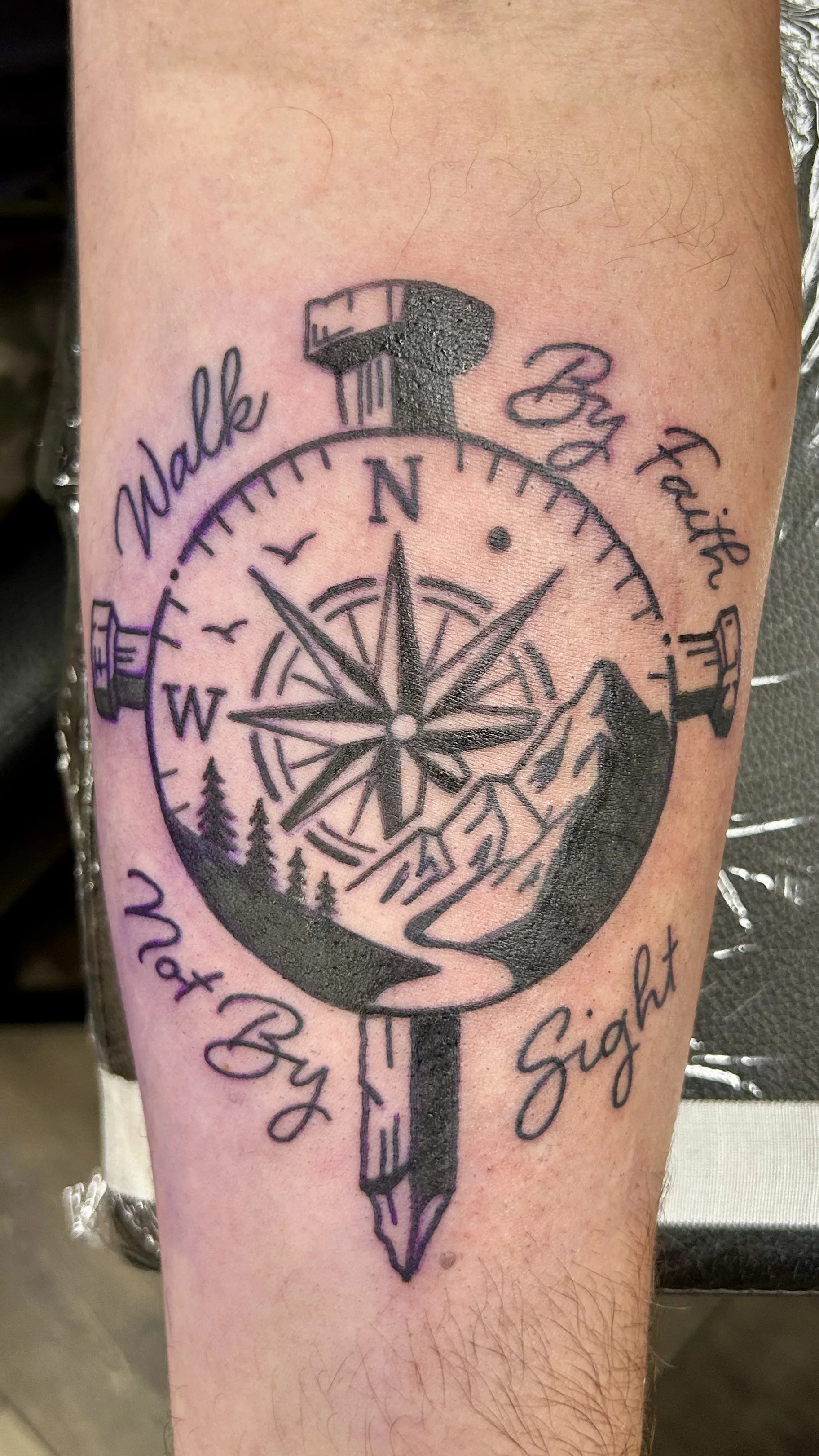 Tattoo of a compass with a mountain landscape in the center, the words "Make It Right" curved around the top, and "Mat By" along the bottom.