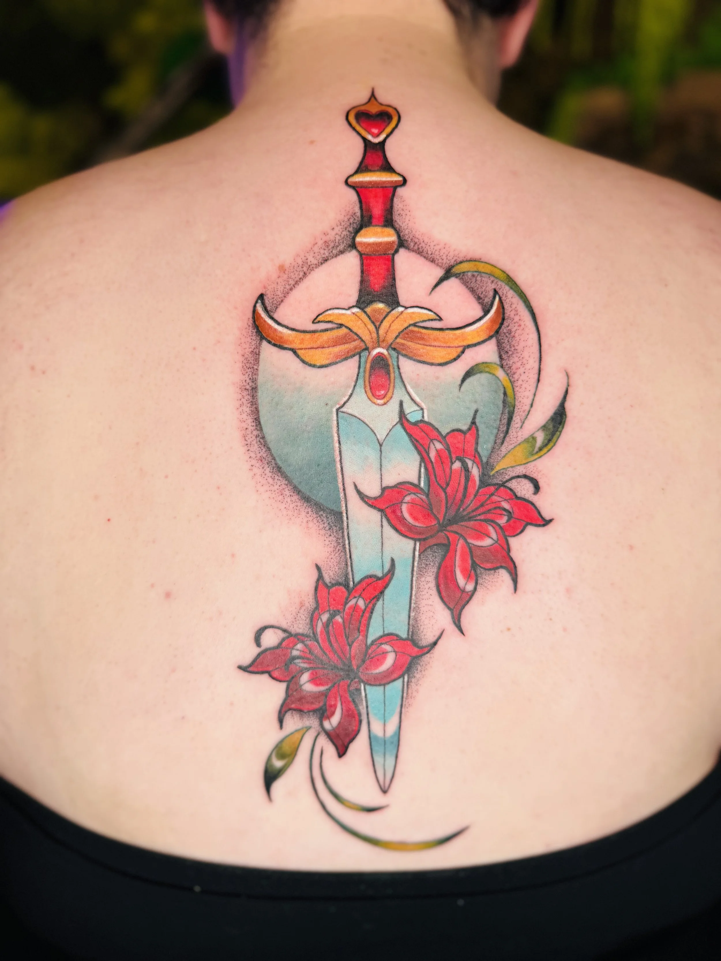 Tattoo of a dagger with a red and yellow handle, red and black details, and red flowers growing from the blade, on a person's upper back/neck area.