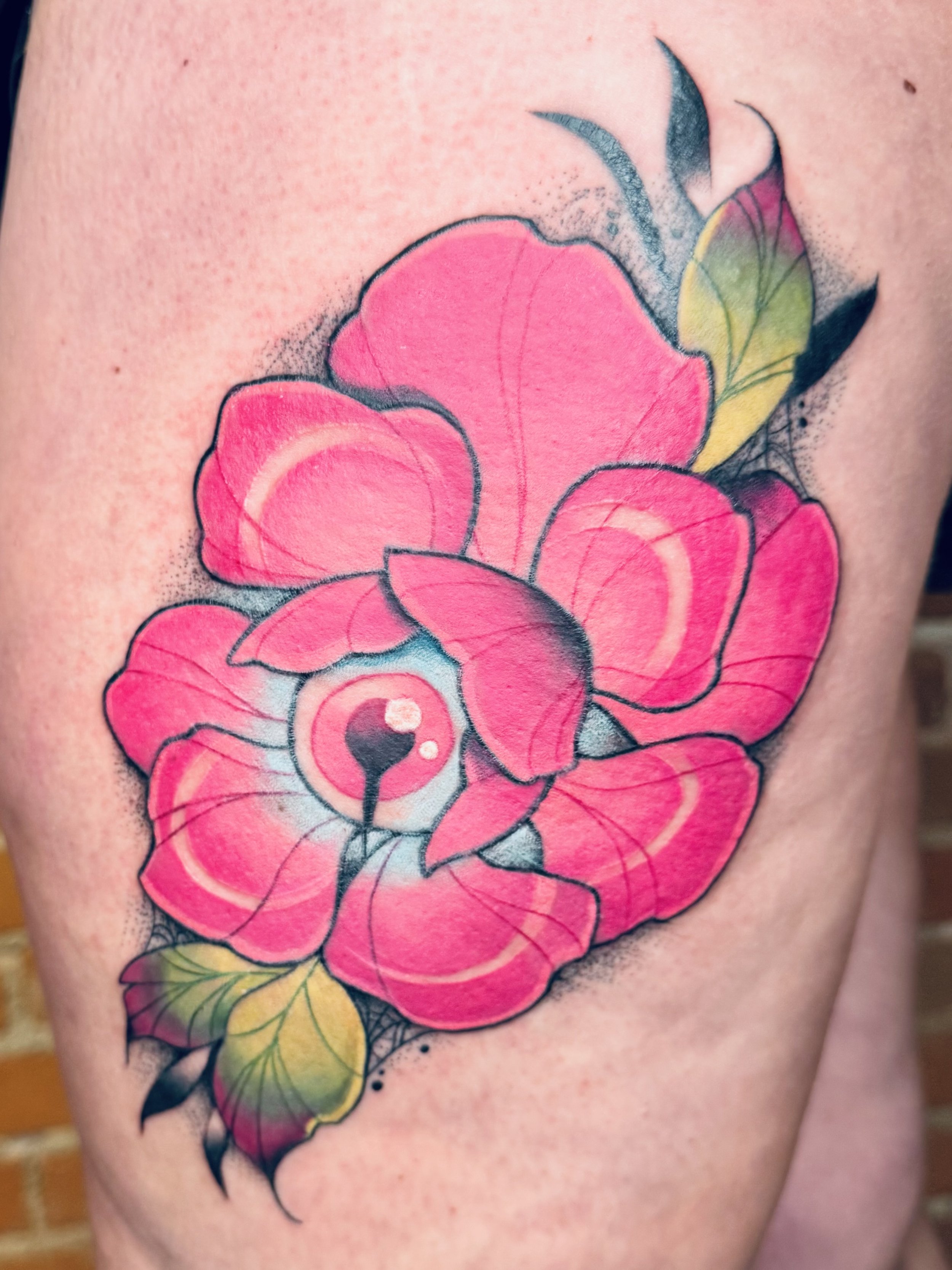 Close-up of a colorful floral tattoo featuring pink, yellow, and green elements on skin.