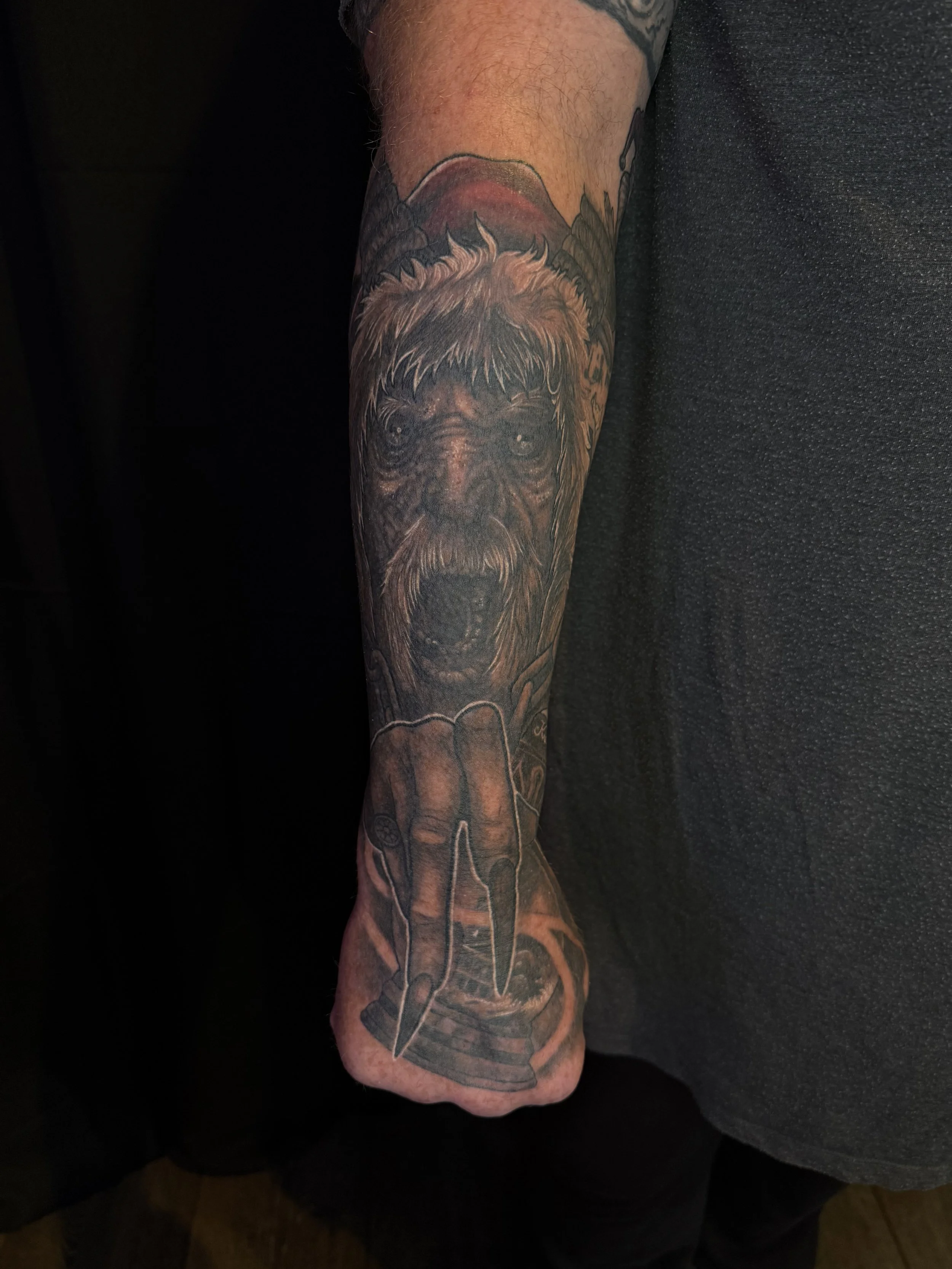 A detailed black and gray tattoo of a dog's face on a person's forearm.