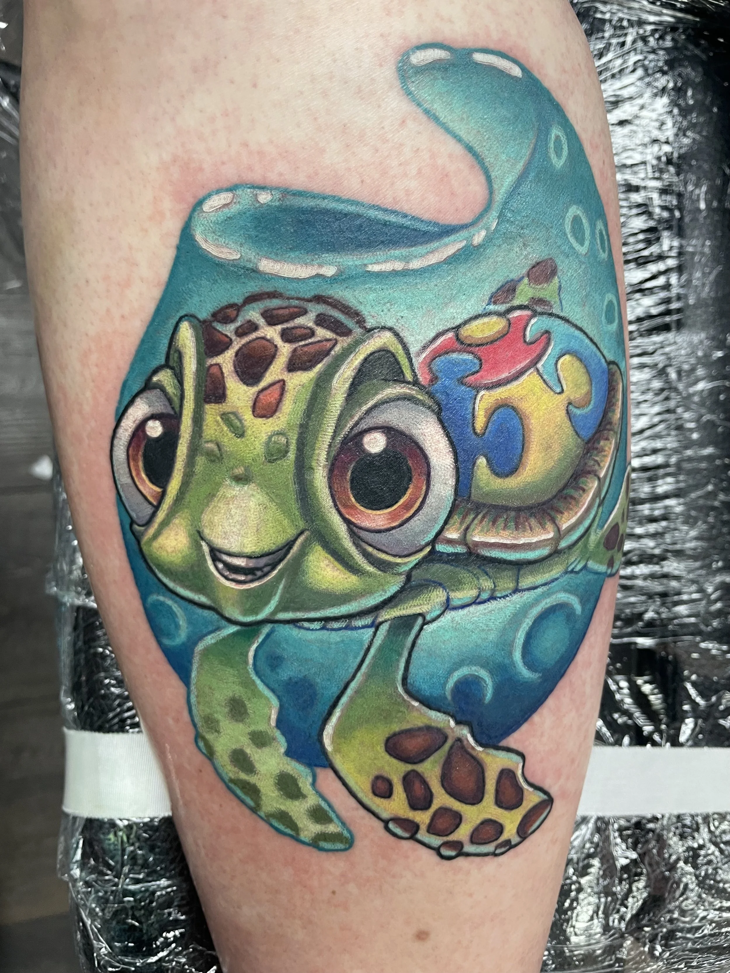 Colorful tattoo of a chameleon with intricate patterns on its back and tail, located on a person's arm.