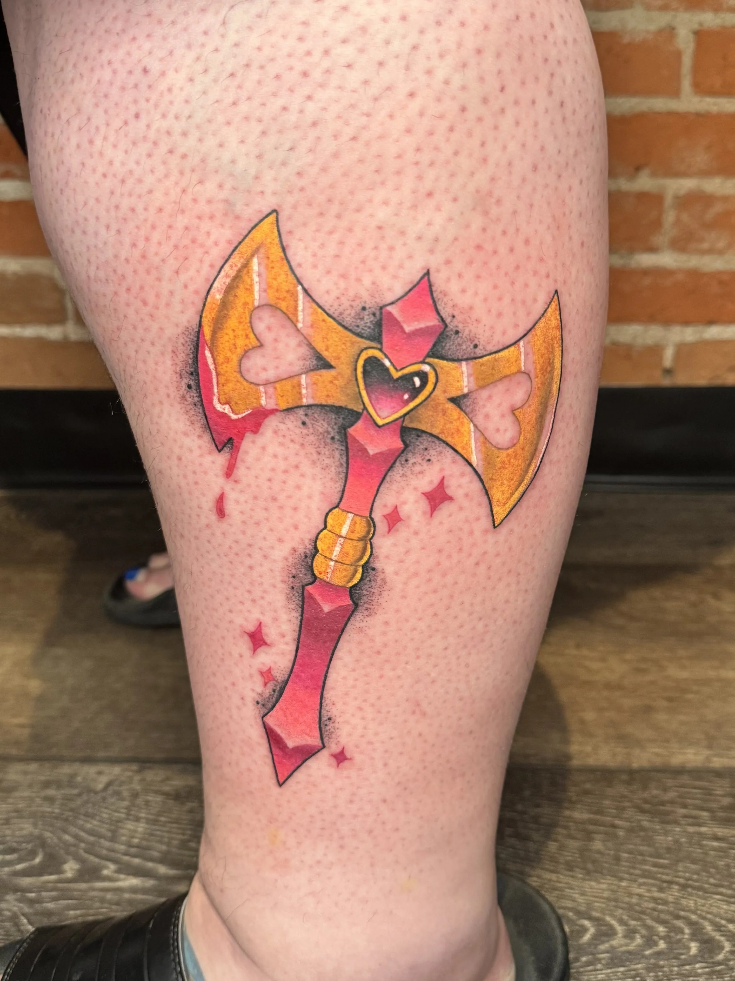 Tattoo of a bow with pink and red accents on a person's calf.