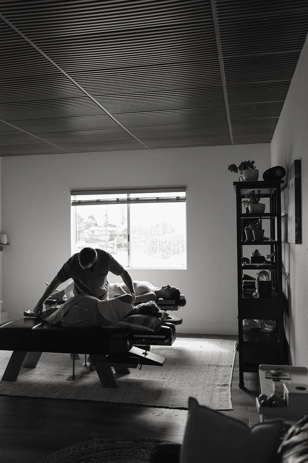 A person receiving a chiropractic adjustment in a room with natural light coming from a window. Brand and lifestyle photography session for Abundant Life Chiropractics in Maui, Hawaii by Rhianon Brown Photography.