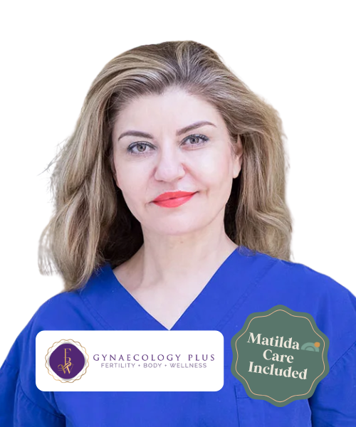 A woman with shoulder-length blonde hair wearing blue healthcare scrubs, standing against a transparent background. There are logos and text on the image indicating it is related to gynecology and wellness, with a note that Matilda care is included.