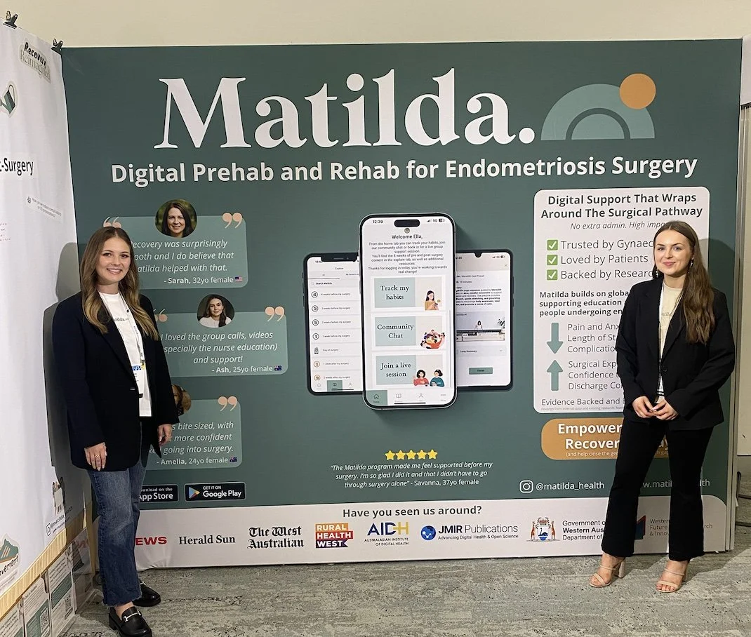 Anna and Alyssa, who have a lived experience of endometriosis and pelvic pain, stand together at the Matilda stand