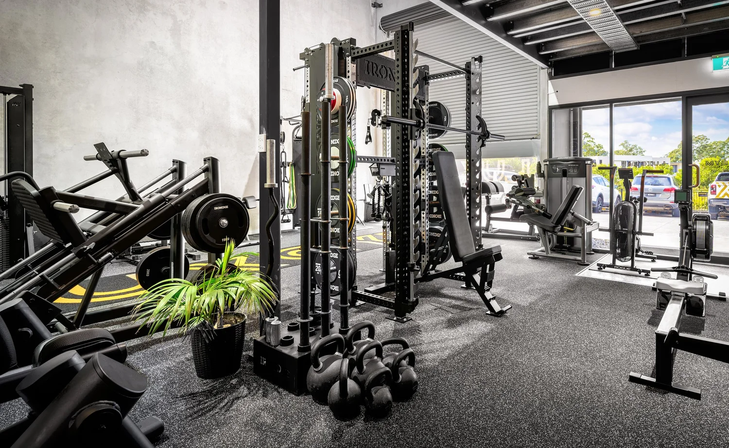 Inside LUXGYM Cooroy: racks, free weights, kettlebells and glass doors in a bright private gym