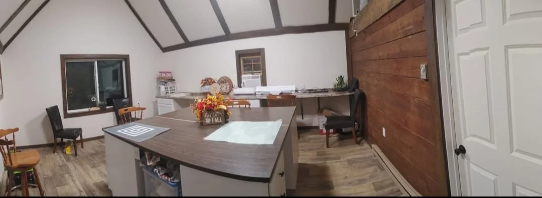 Kitchen with wooden ceiling beams, a dark wooden dining table, a small island, chairs, and a window with a view outside.