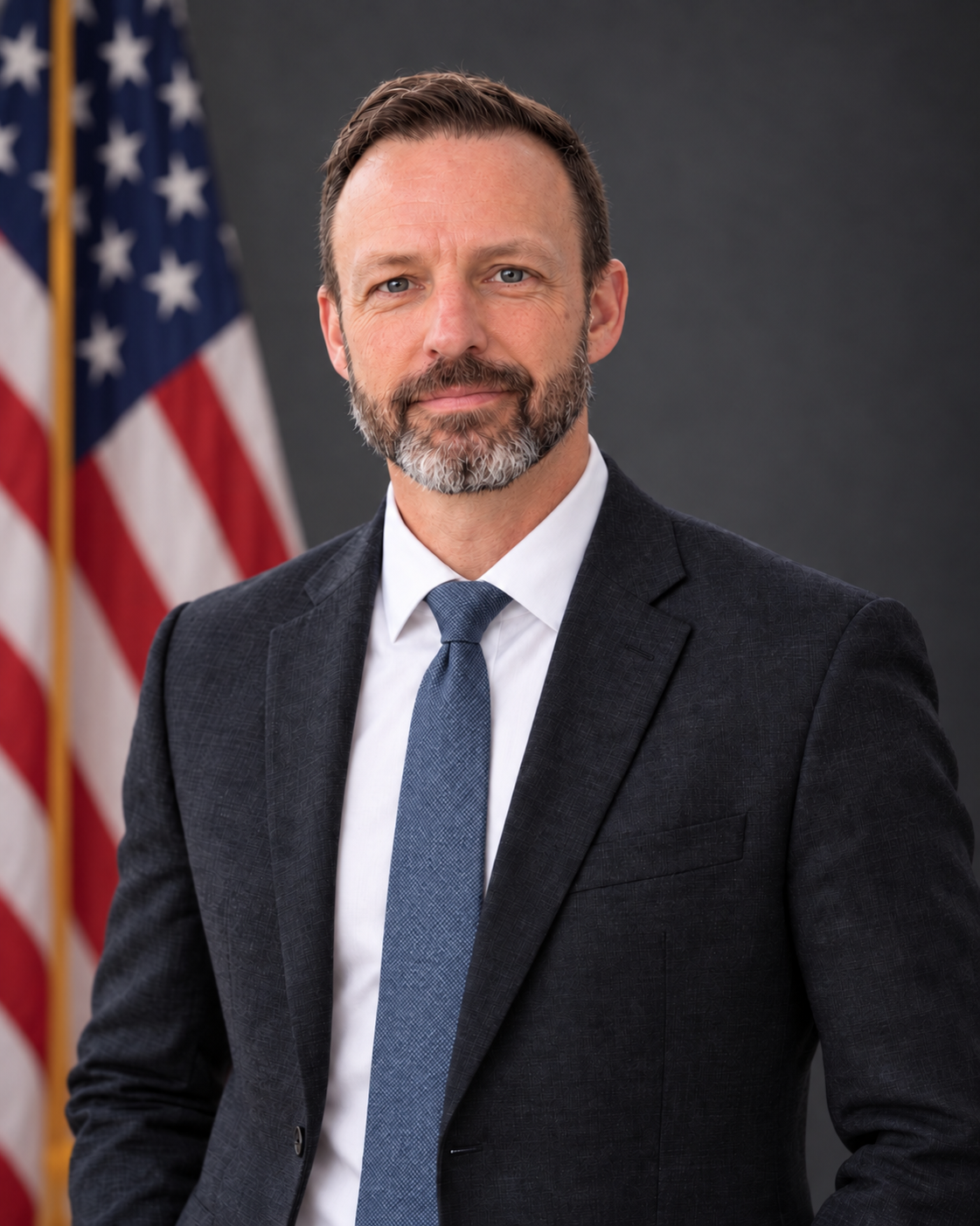 Trey Treadwell, founder of Surnia Advisory, wearing a dark suit and blue tie with an American flag in the background.