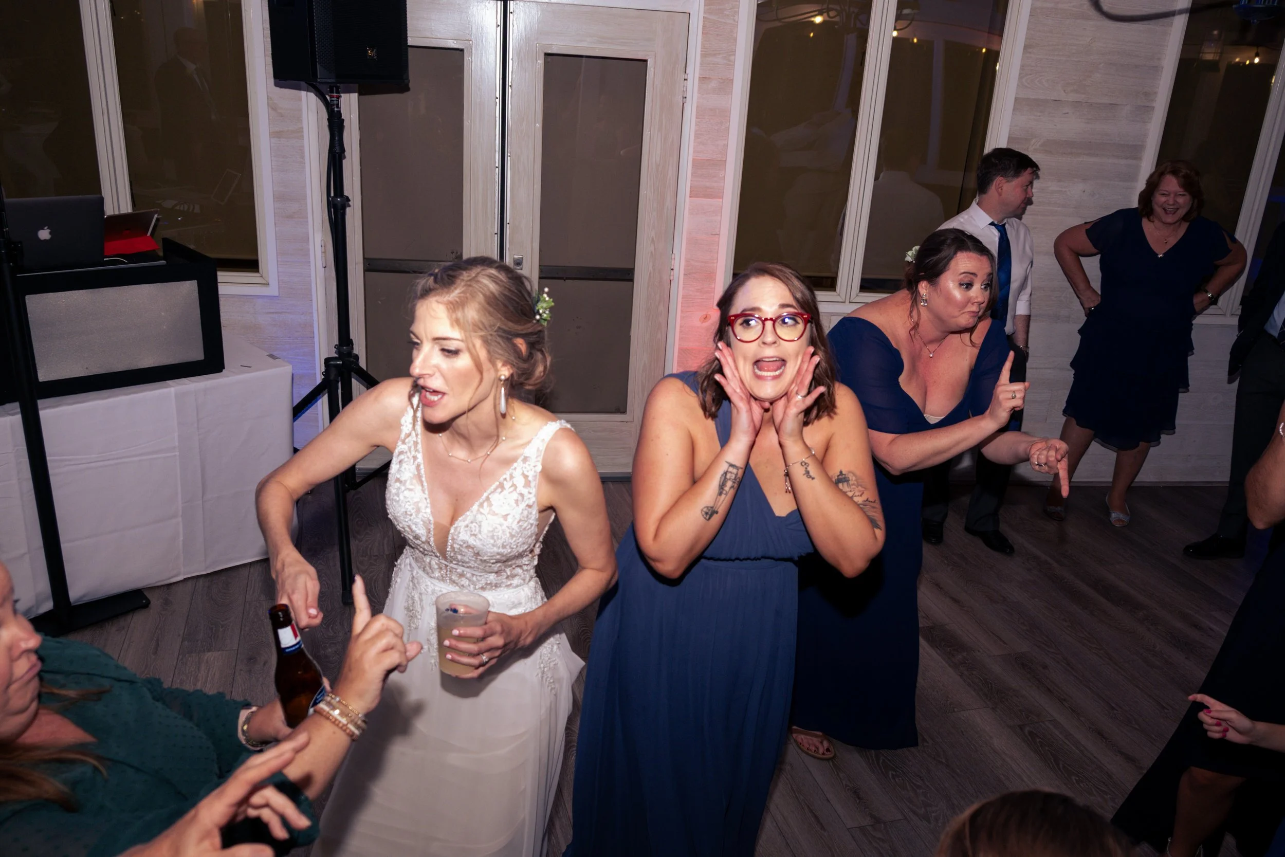 Group of people dancing and having fun at a celebration or party in a decorated room, with some individuals holding drinks.