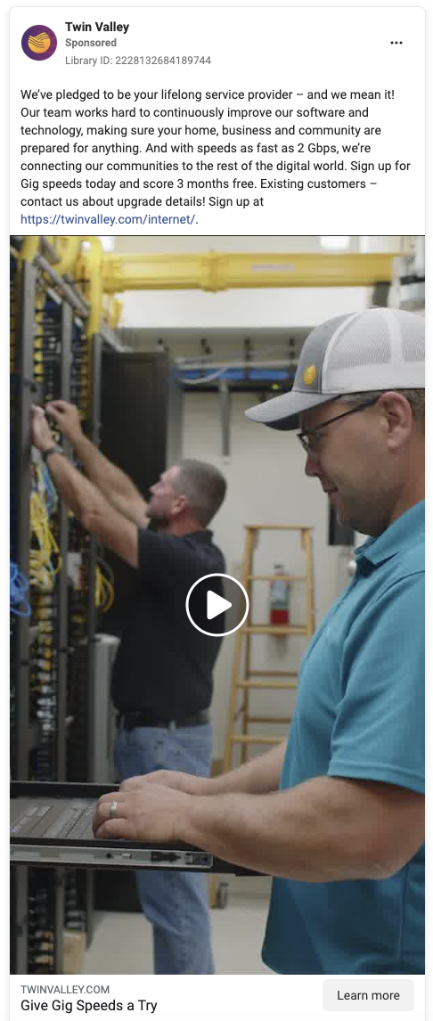 Two men working in a server room; one is at a rack connecting cables, the other is using a laptop.