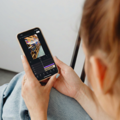 Person using a smartphone to edit a photo or video, sitting on a couch.