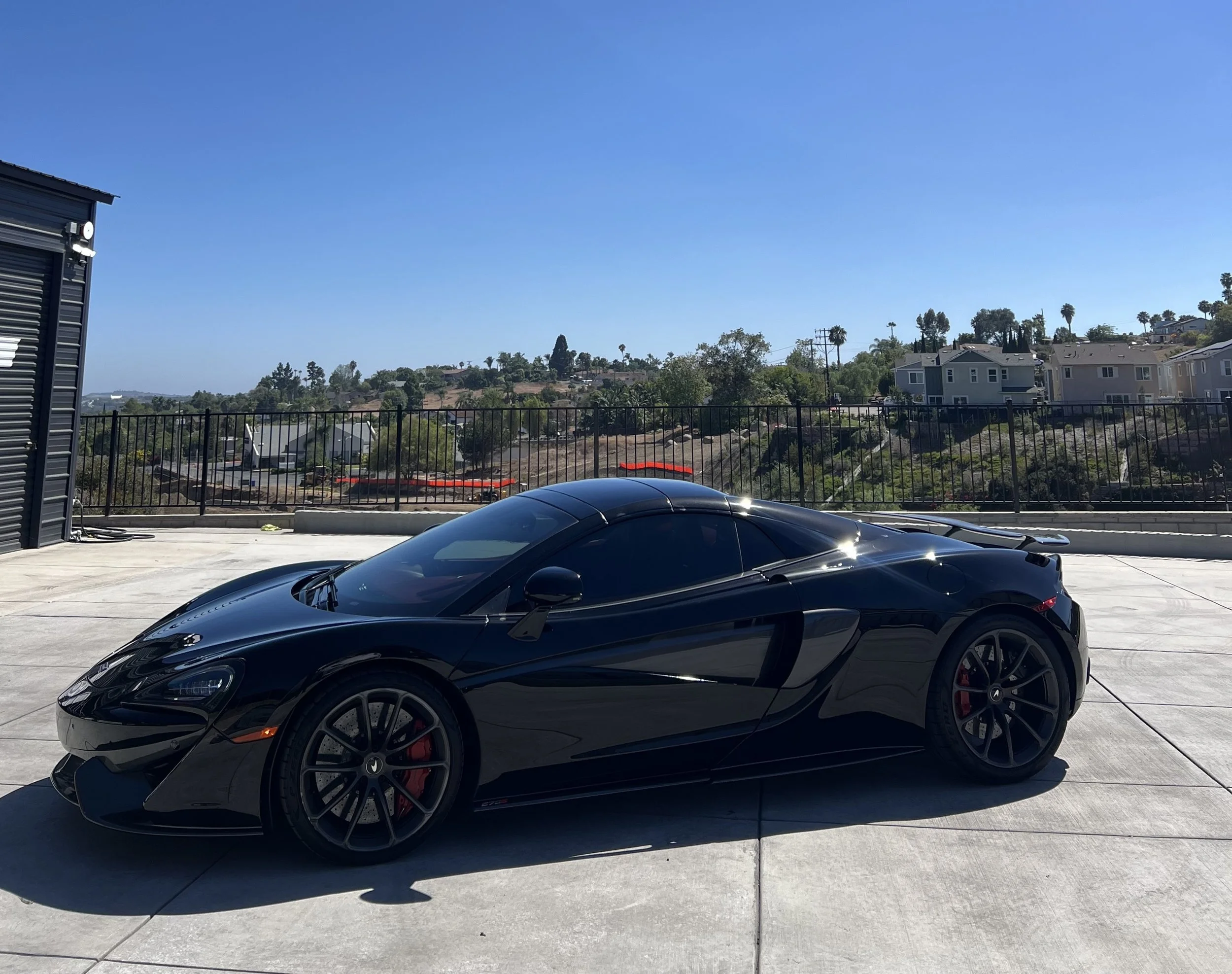 A black McLaren sports car with window tinting to protect the interior dashboard and seats done by Reborn Motorwerks.