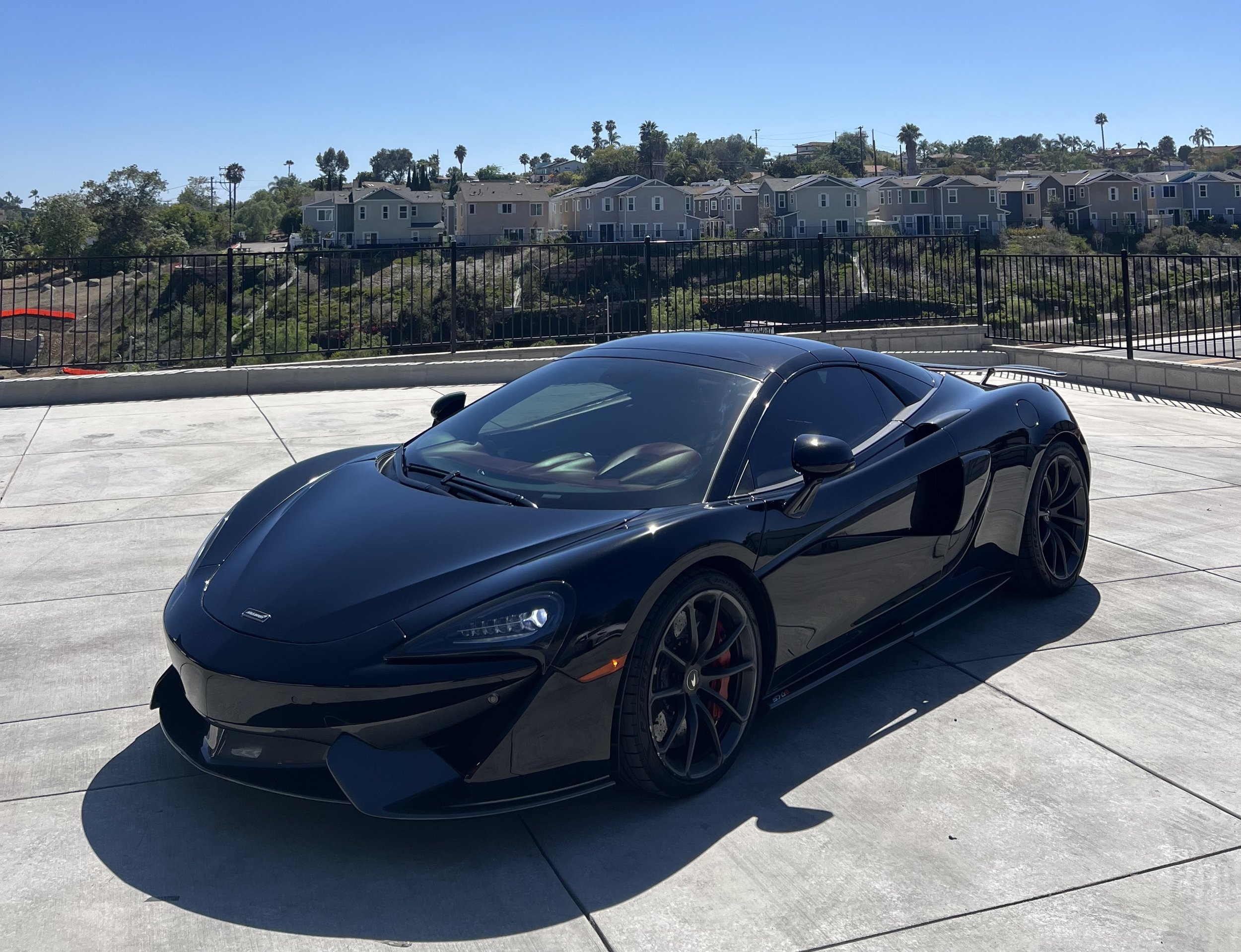 A black McLaren sports car with window tinting to protect the interior dashboard and seats done by Reborn Motorwerks.