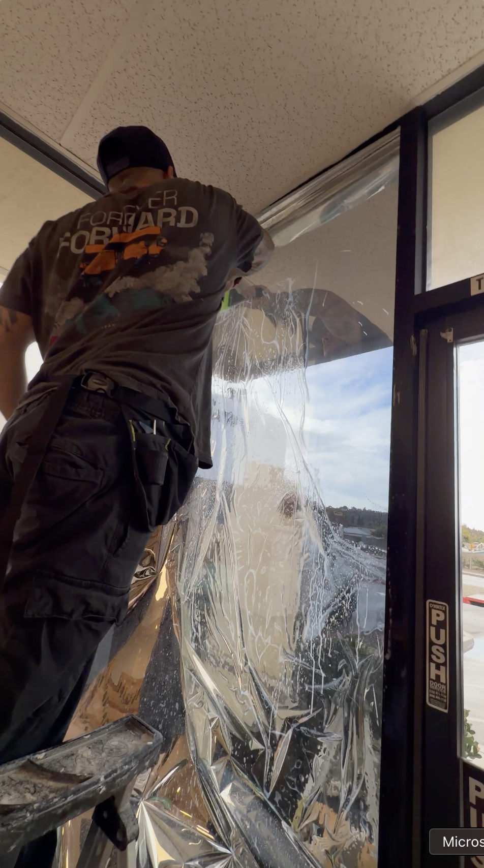 Window tint being done in a commercial office to protect employee's from glares, UV rays, and privacy done by Reborn Motorwerks.