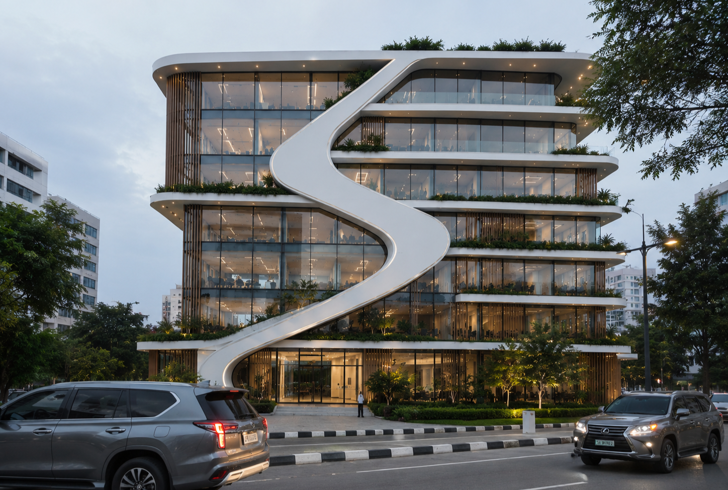 Modern multi-story office building with large glass windows, featuring a prominent white spiral slide on its exterior, surrounded by cars and trees in an urban setting at dusk.
