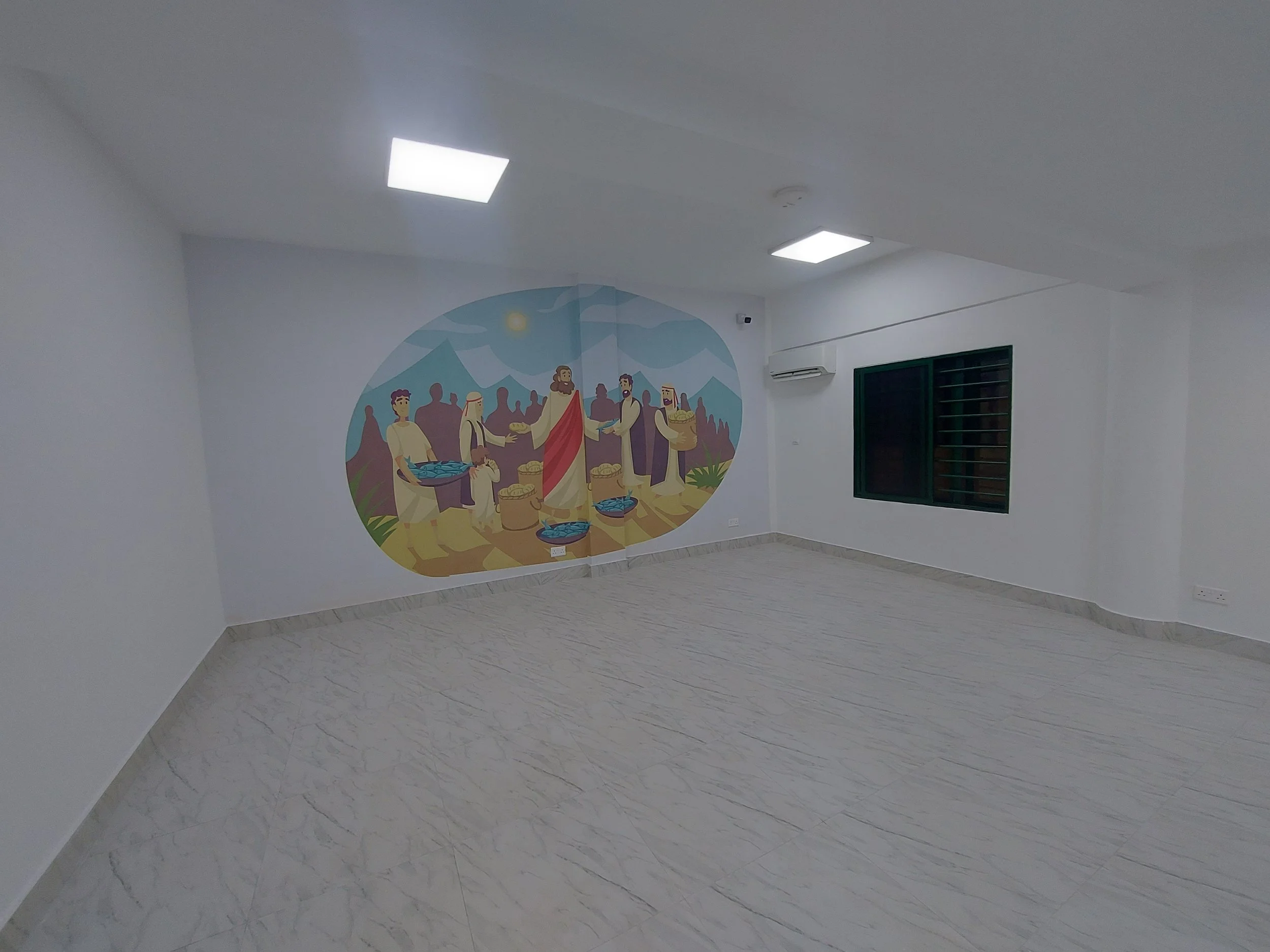 A mural depicting a biblical scene of Jesus Christ with people around him, in a room with white walls, ceiling lights, a window, and an air conditioner within the children’s church building (RCCG Olive Branch) Project Managed by IHOD.