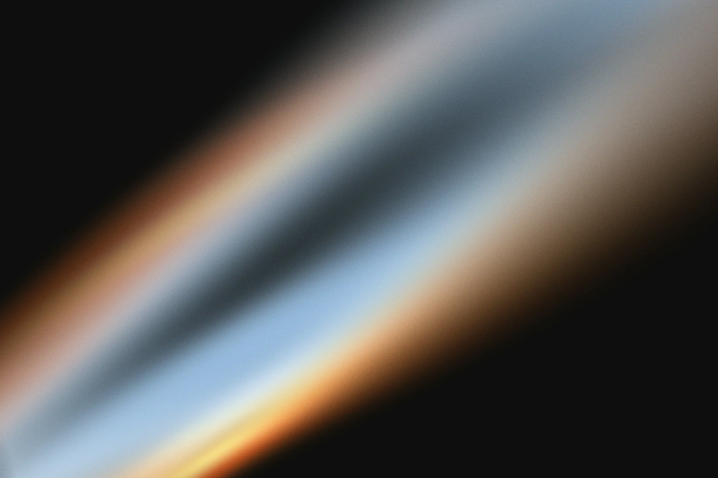 Blurred abstract image with gradients of black, blue, beige, and white colors.
