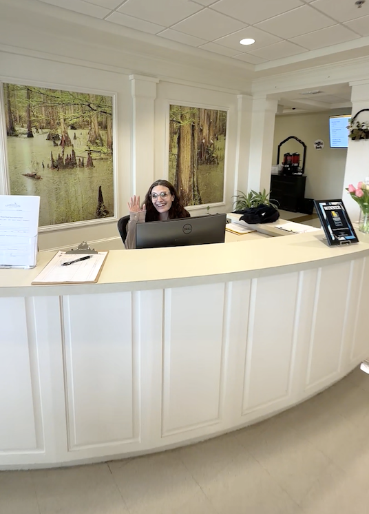front desk representative waving and smiling