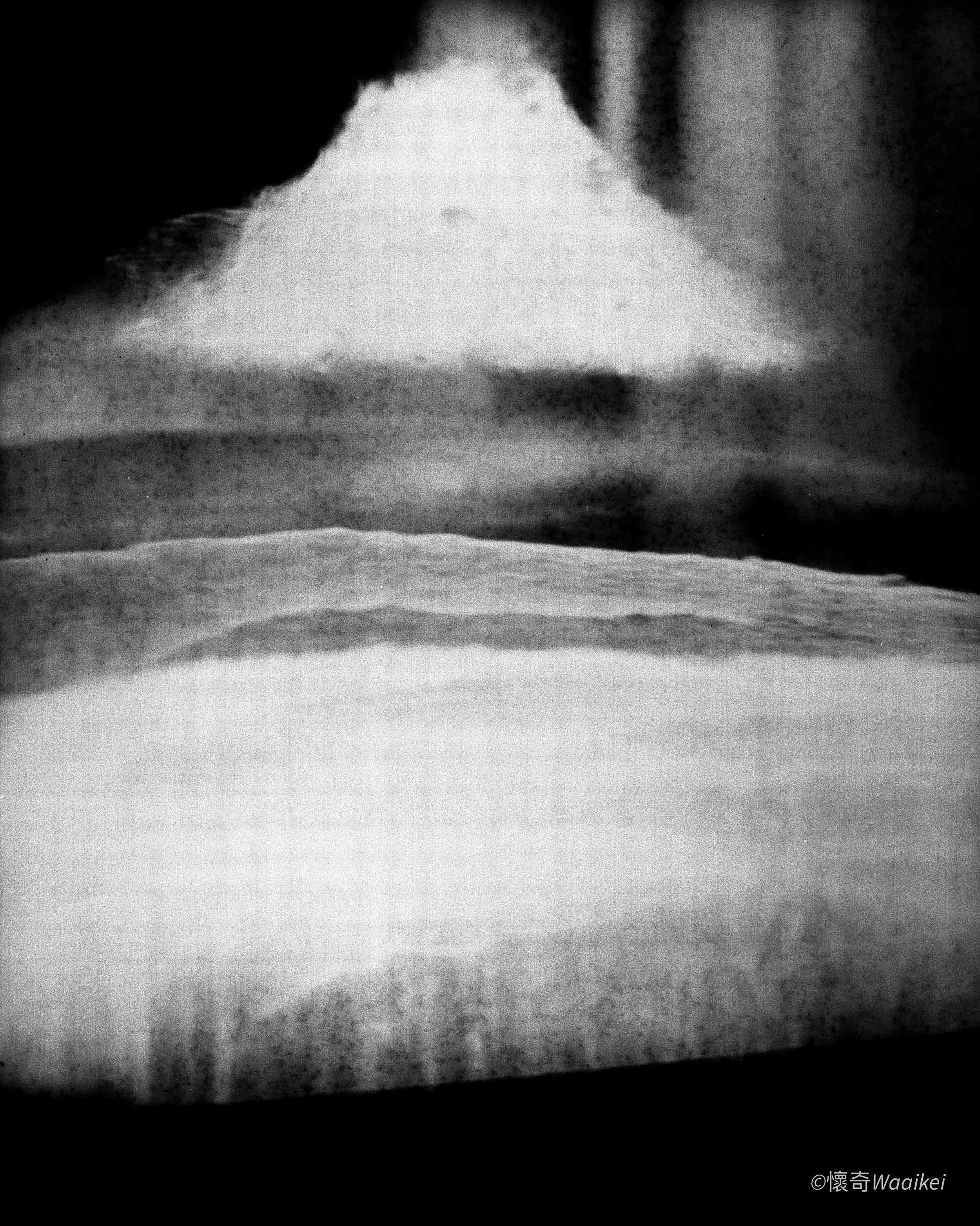 Close-up of a white snow-covered mountain with a dark sky and clouds in the background, black-and-white photograph.