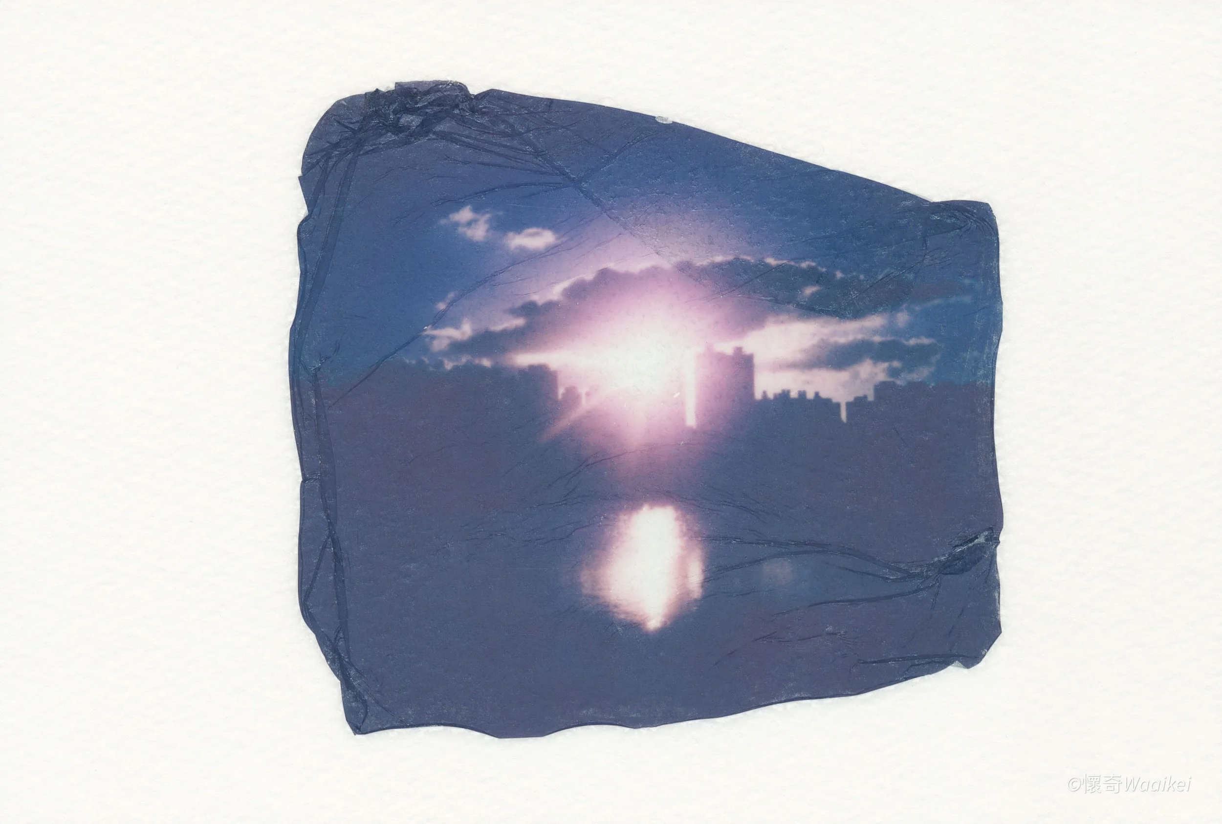 A torn piece of black plastic or film displaying a city skyline with tall buildings and a sunset or sunrise sky with purple and orange hues.