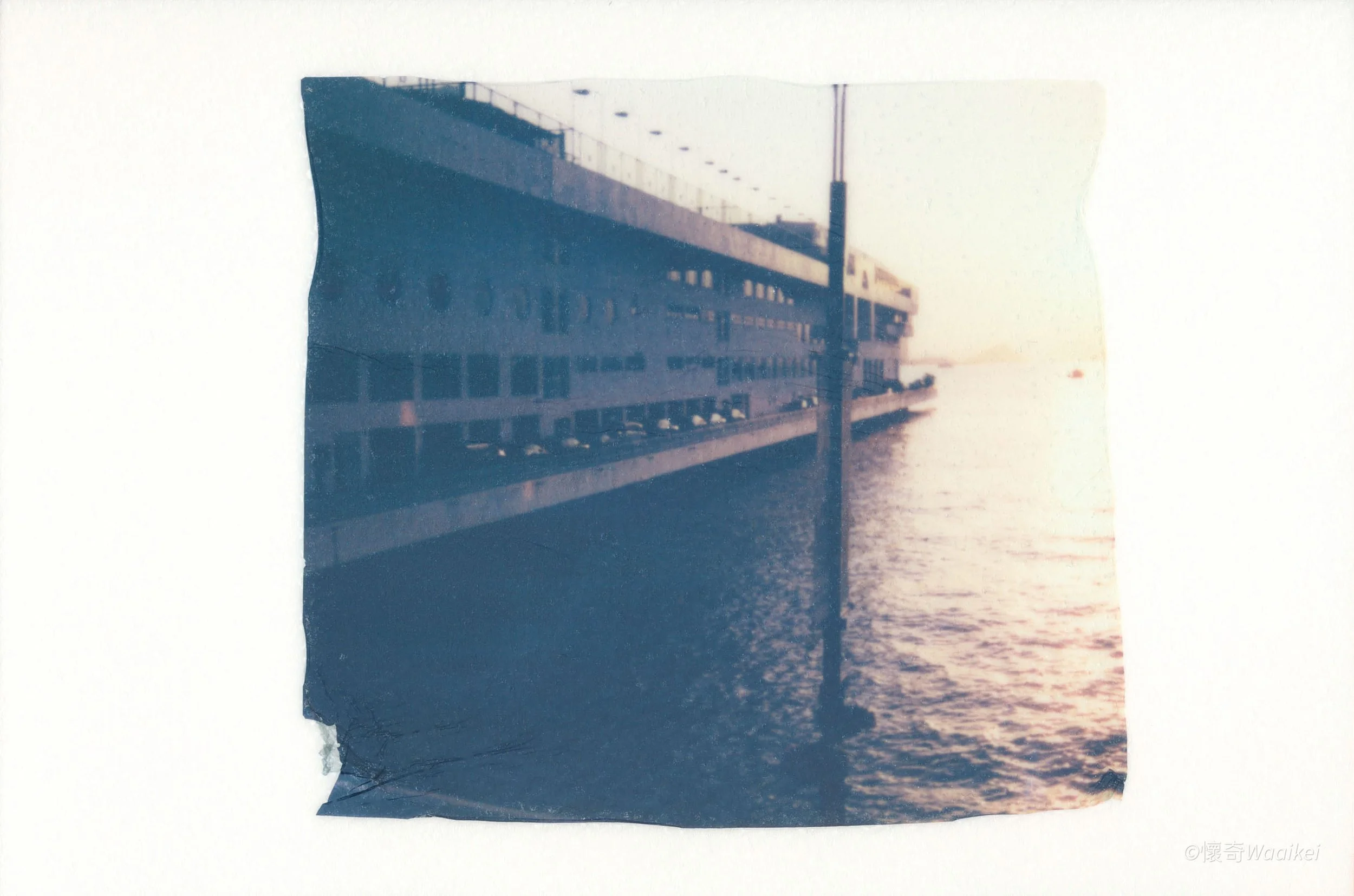 A blurry photograph of a building by the water during sunset or sunrise.