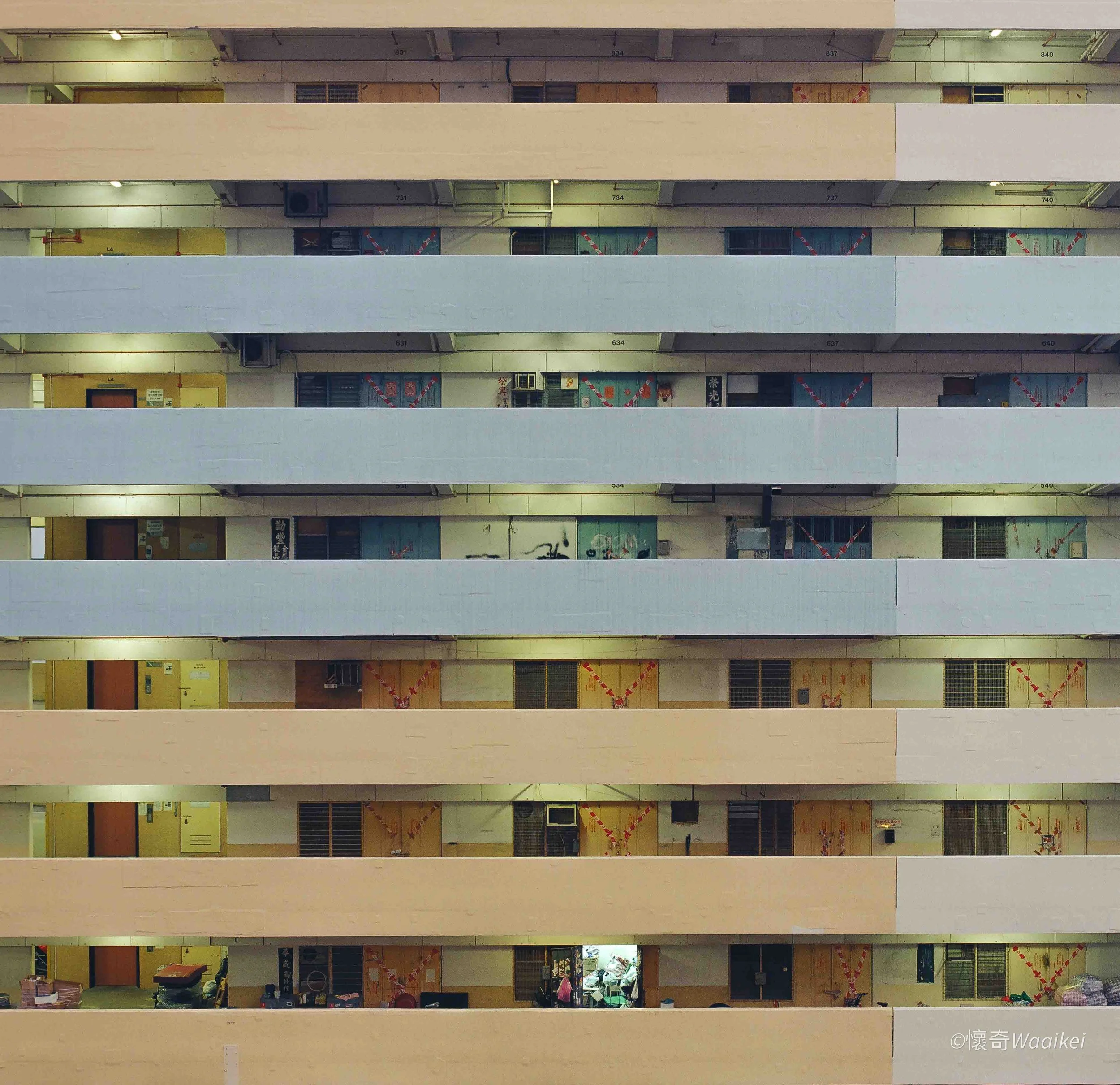 Multiple floors of a building with open balcony spaces, some windows and doors, construction or renovation signs, and various objects and decorations inside.