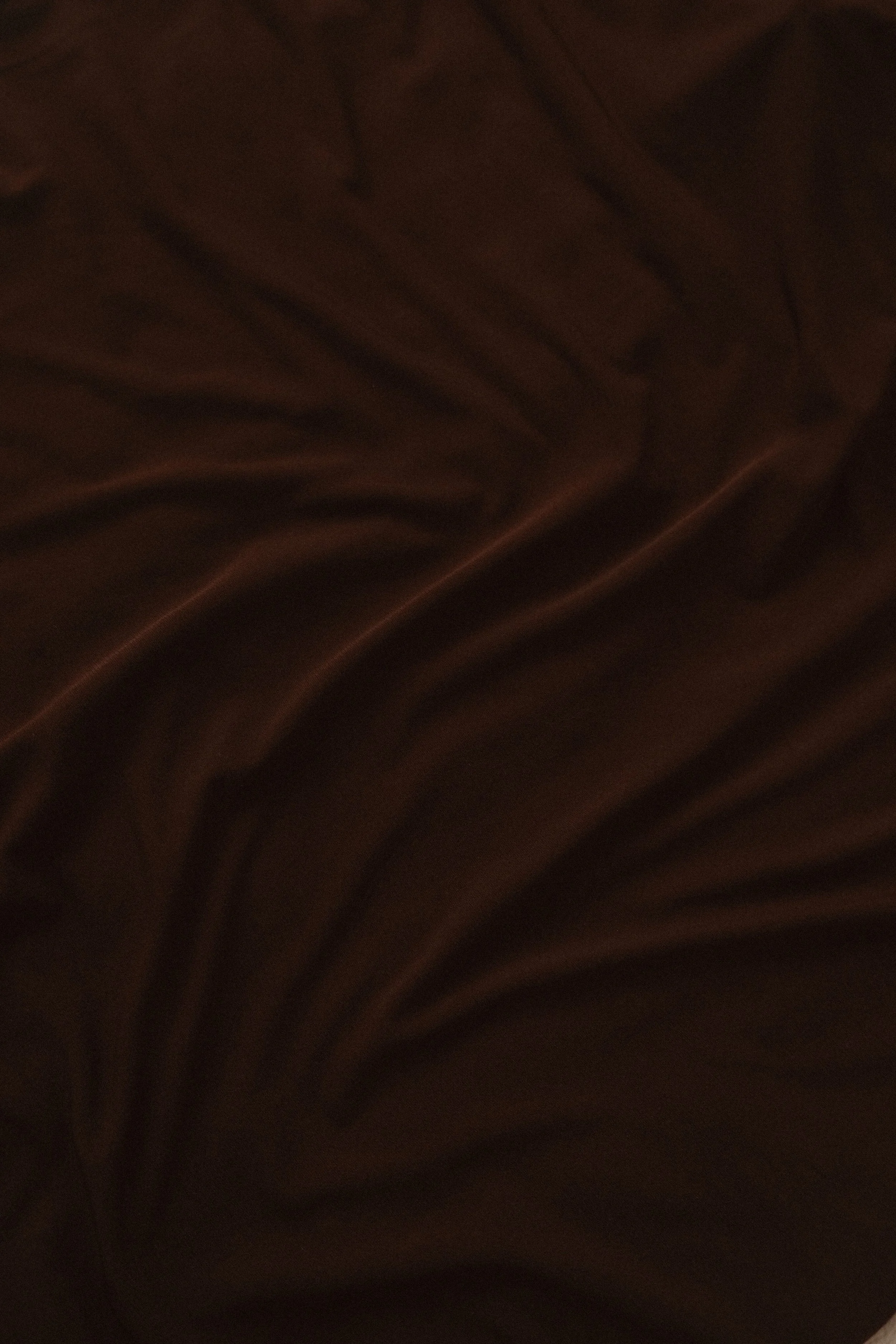 Dark brown fabric with visible folds and creases.