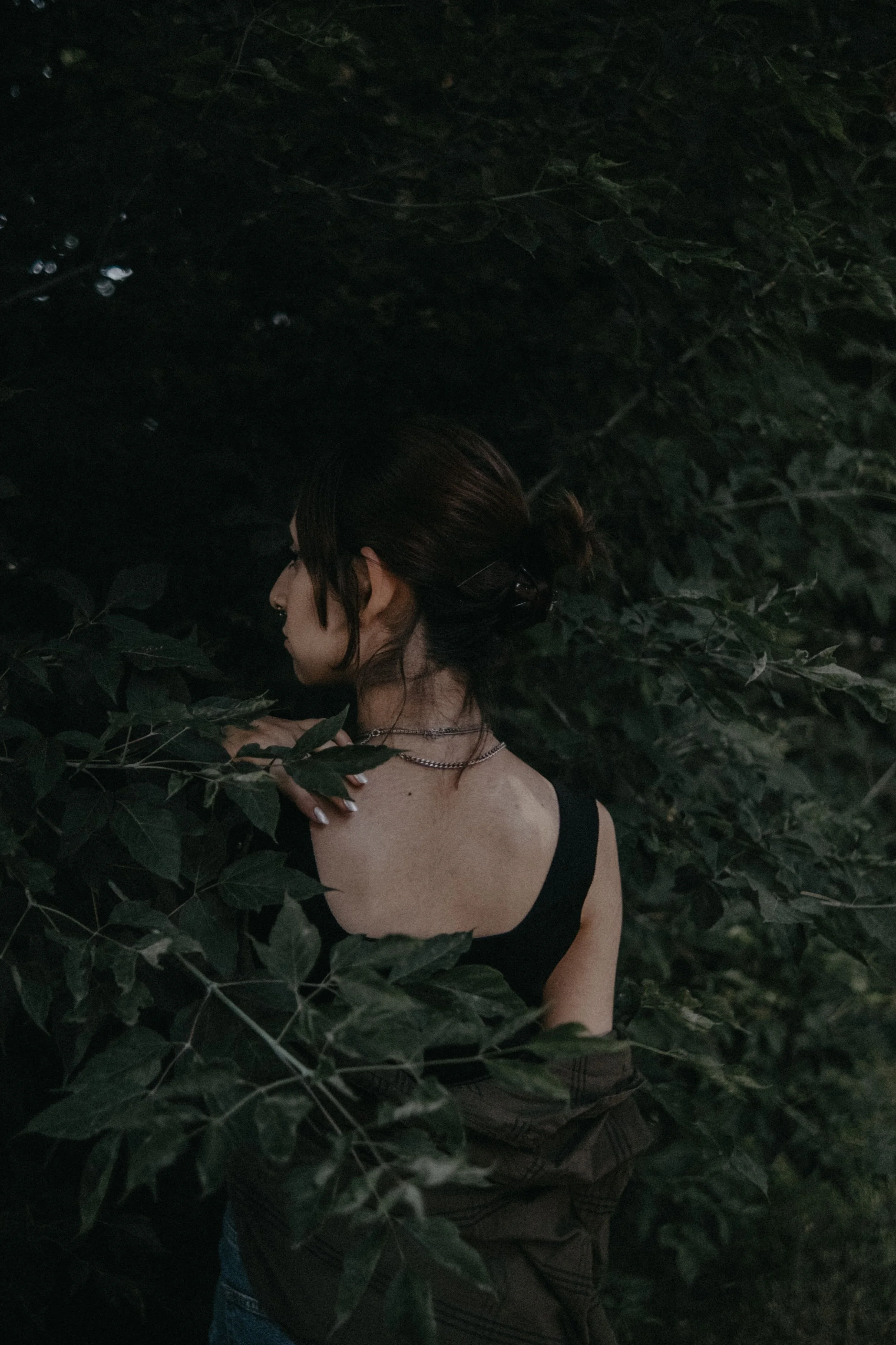 Woman standing quietly among dense green foliage