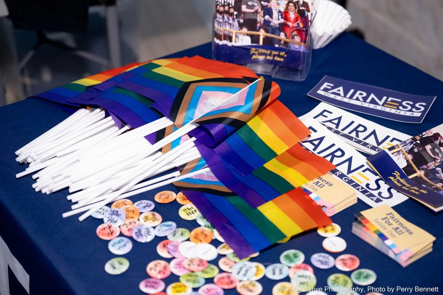 A table displaying rainbow flags, campaign flyers with 'Fairness Virginia,' and buttons with various messages supporting LGBTQ+ rights.