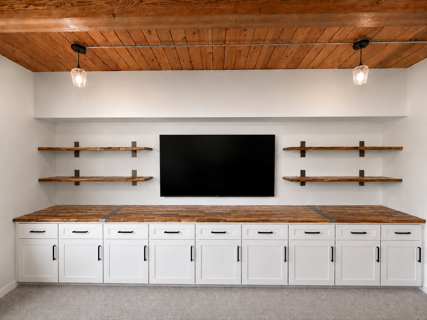 Living room wall with two wooden shelves, a black flat-screen TV, and white cabinets with black handles.