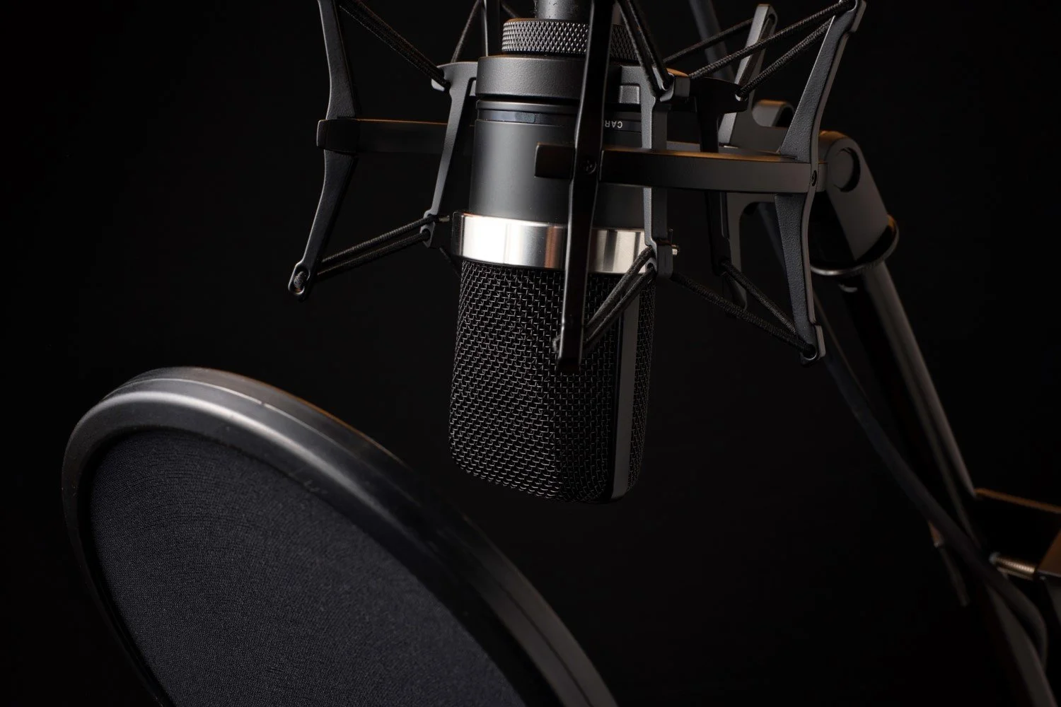 Studio microphone with isolation shield on black — where Poem Cast, Nathaniel Perry's horror poetry podcast, is recorded