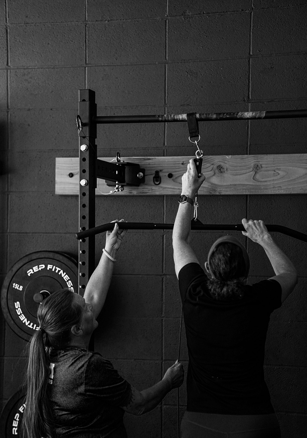two woman assisting each other in reaching a high piece of equipment