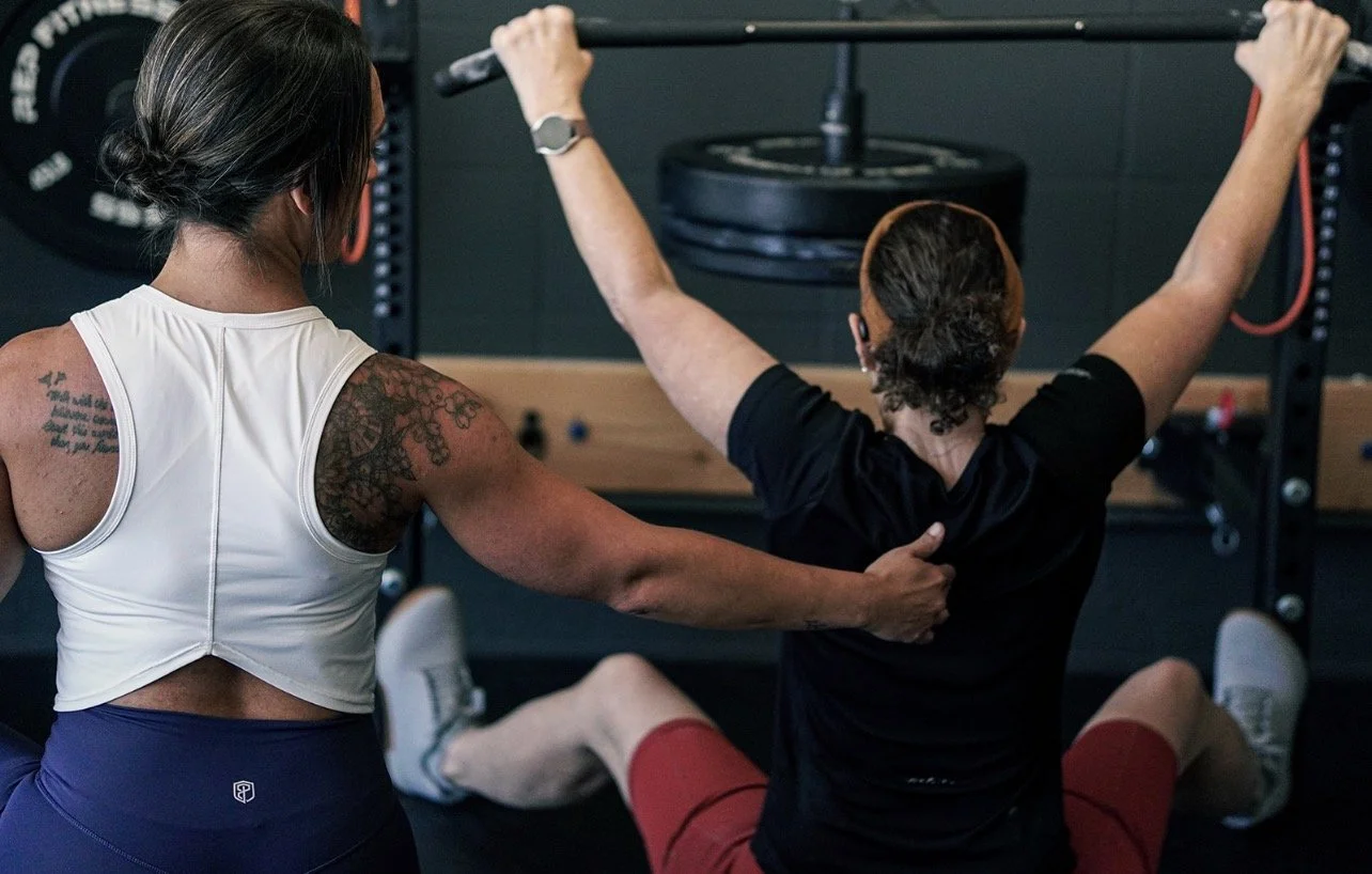 coach assisting woman by identifying location in athletes spine