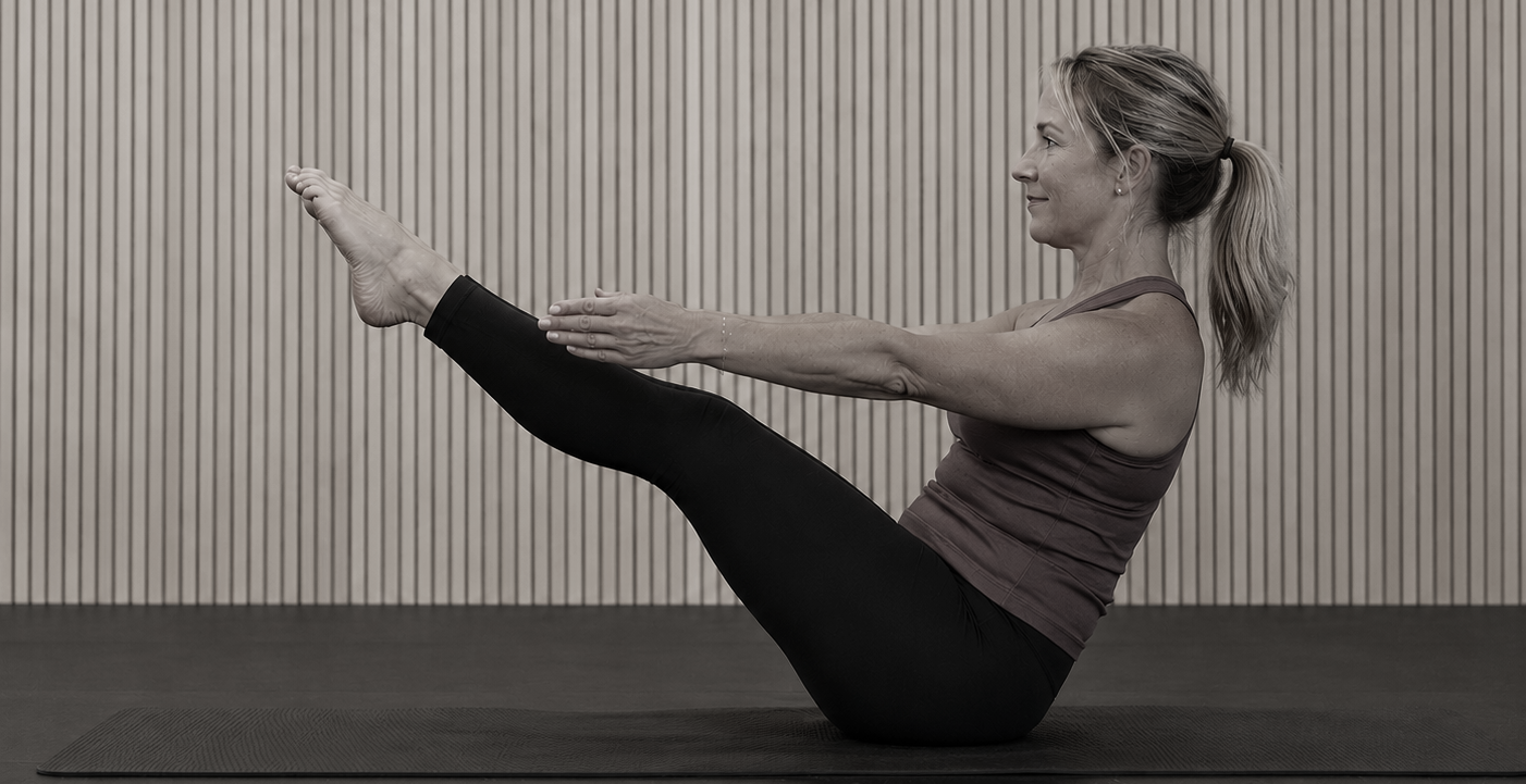woman sitting on the floor with her legs up and arms reaching for her toes in a mat pilates pose at strength and grace collective a woman only gym in forest grove oregon