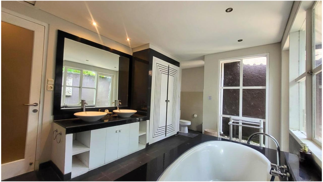 Modern bathroom with a double vanity featuring two vessel sinks, a large mirror, a white toilet, a bathtub, and large windows providing natural light.