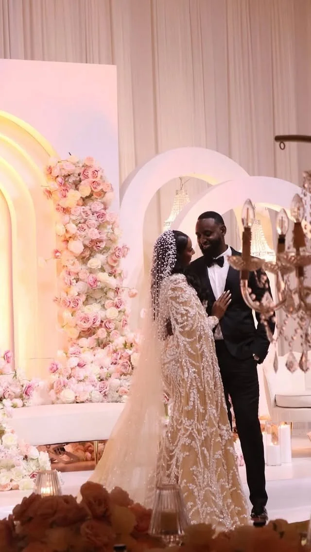 Bride and groom dancing at their wedding, surrounded by floral decorations and elegant lighting.