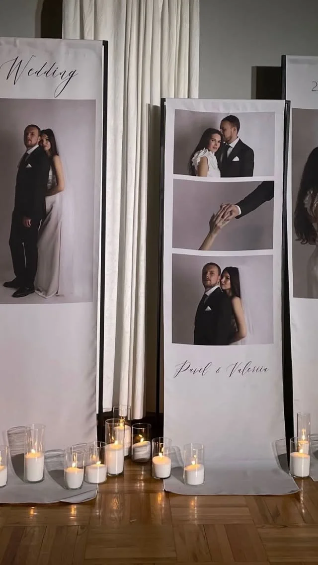 Wedding photo display with three large vertical posters of a bride and groom, candles at the base, and a white curtain in the background.