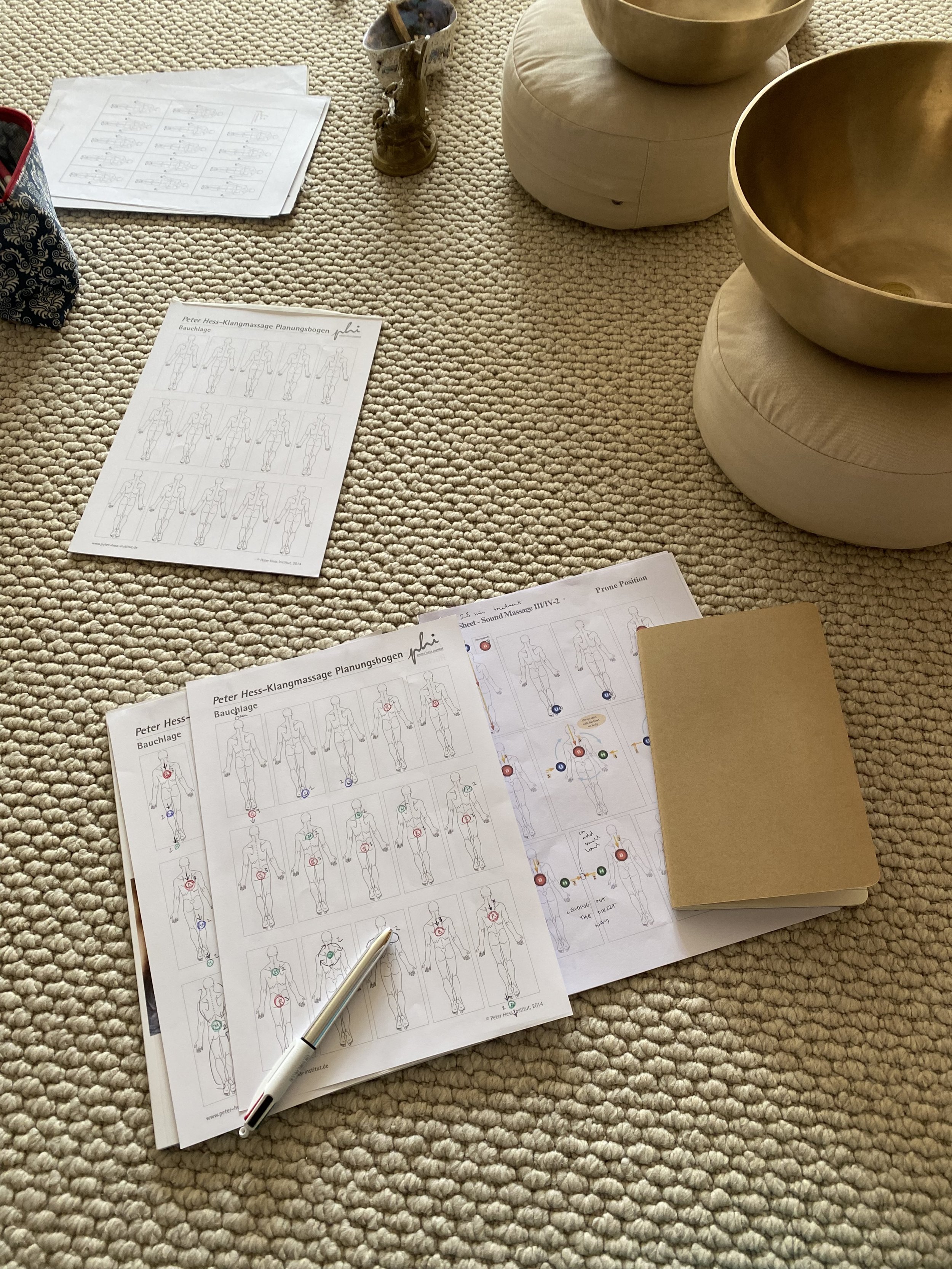 Study notes and pen, next to sound bowls