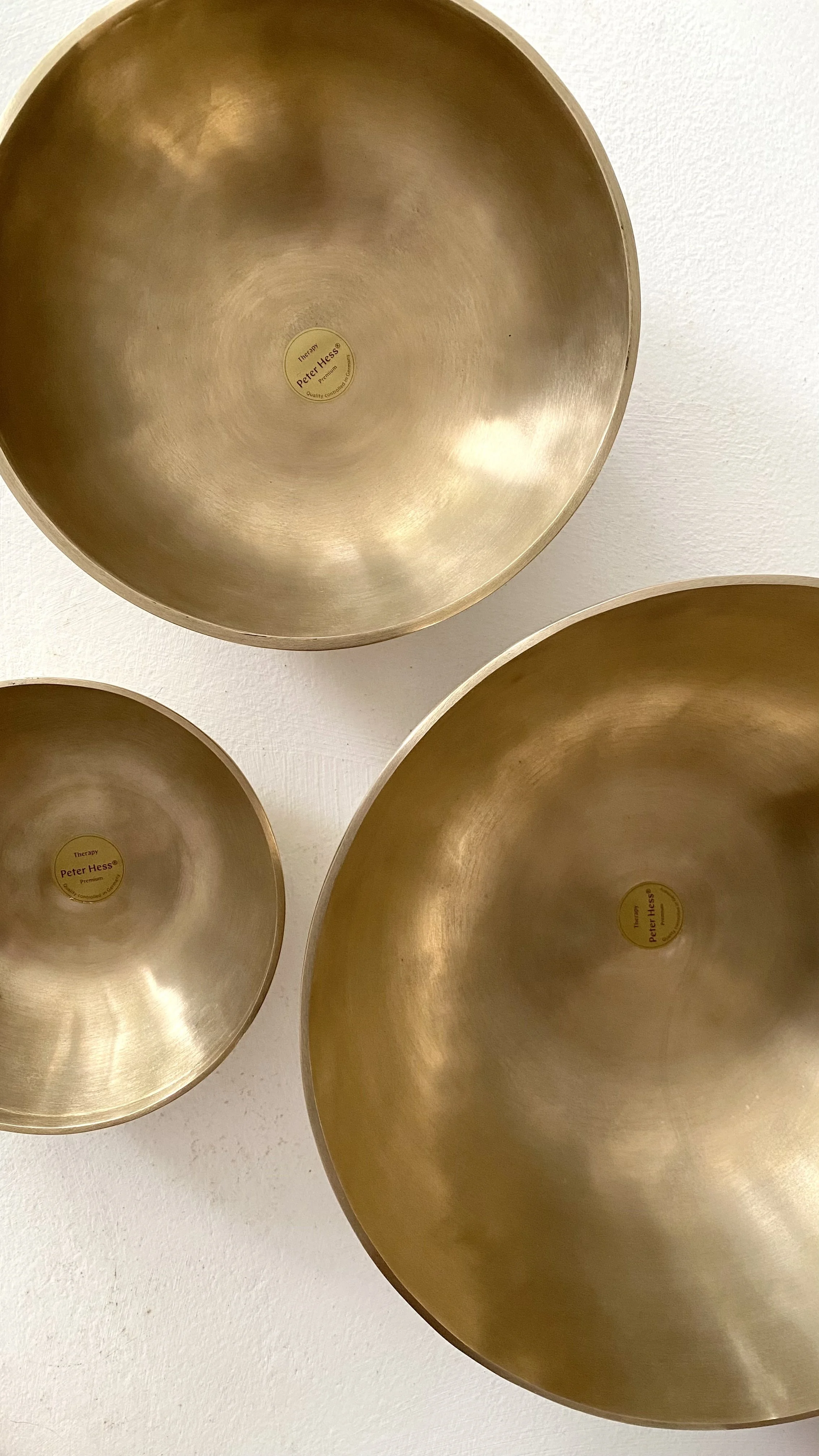 Brass-coloured therapeutic sound bowls on white surface