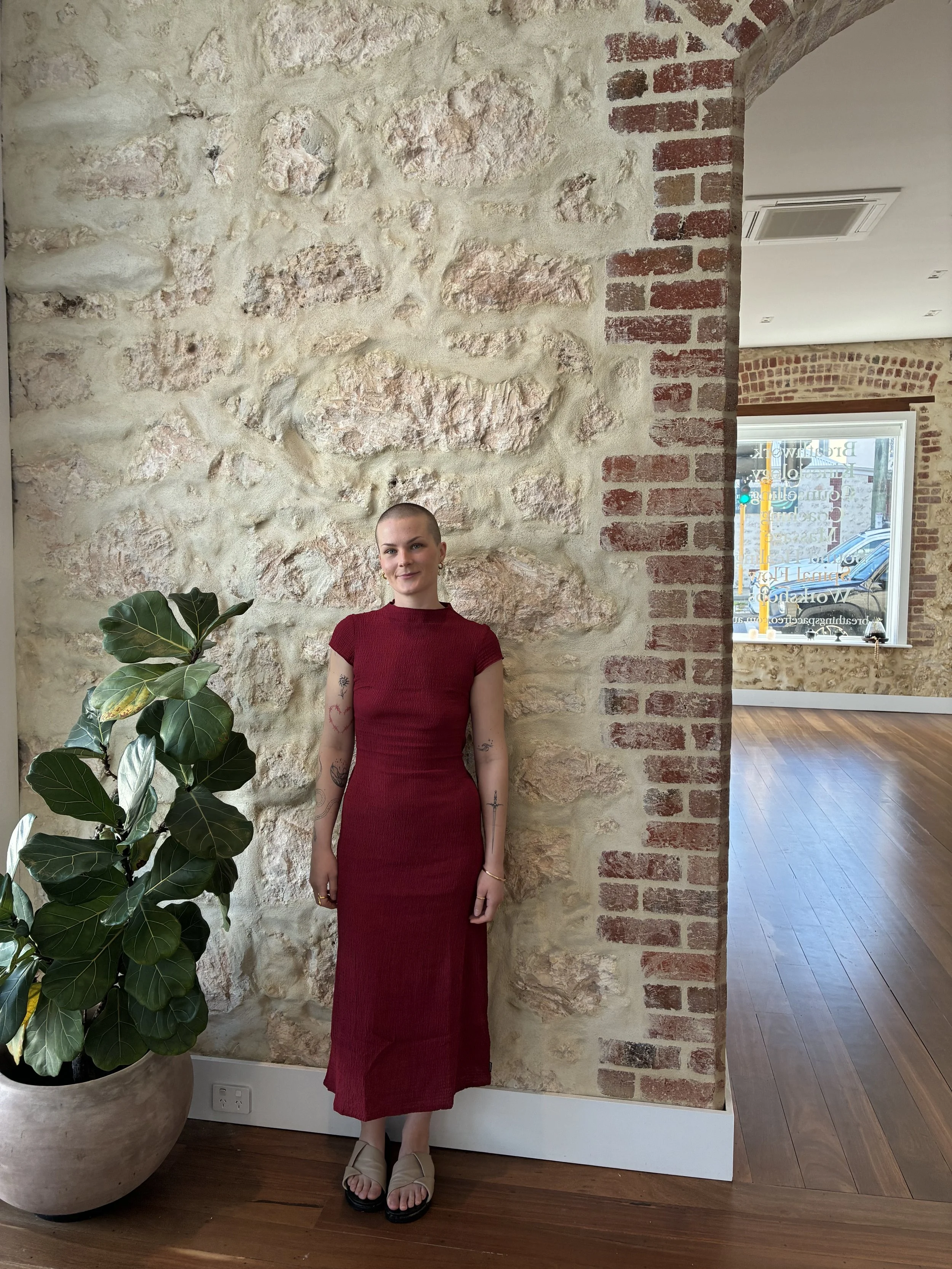 Image of a woman in a dress dress standing against stone wall